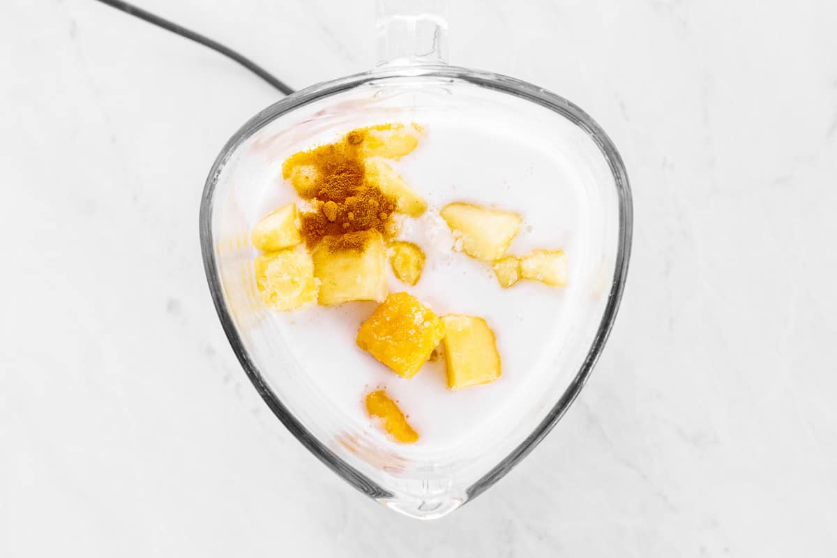 Mango smoothie ingredients piled in a blender.