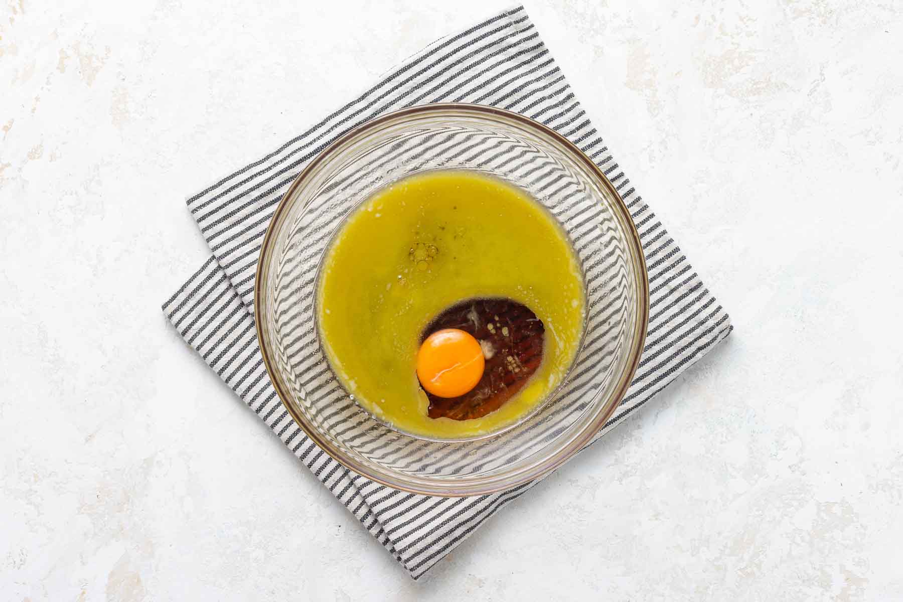 Melted butter, maple syrup, and egg in clear glass bowl.