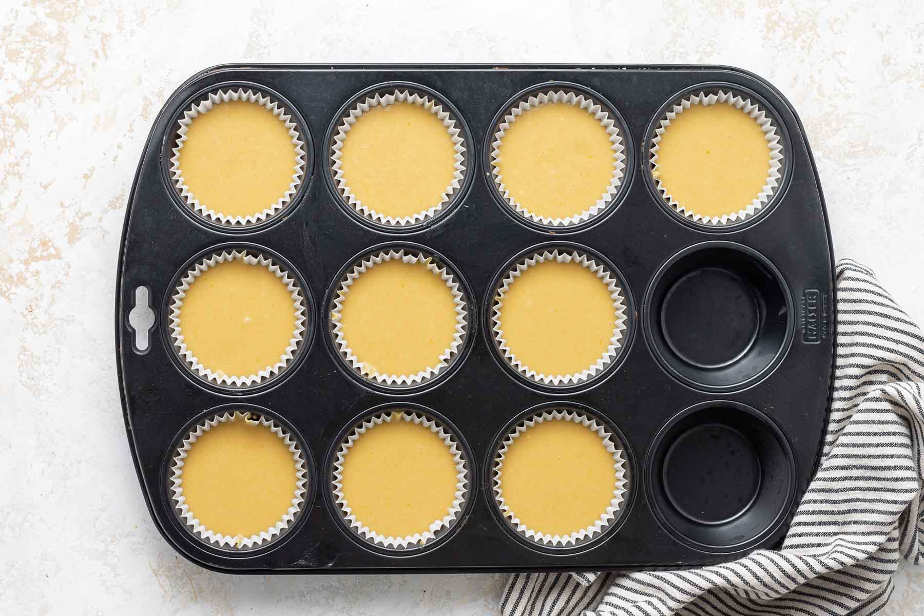 Yellow cupcake batter in muffin pan.