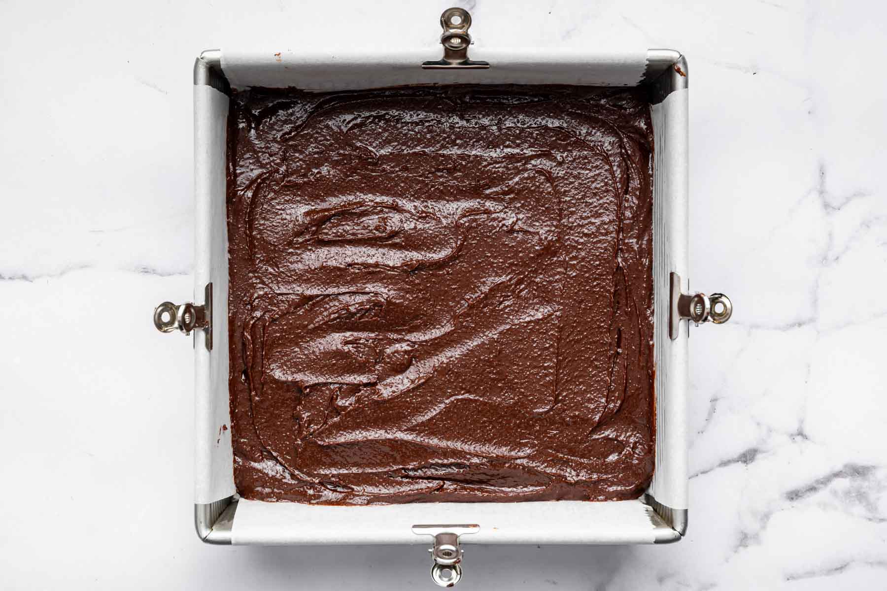 Raw chocolate batter in a metal square pan.