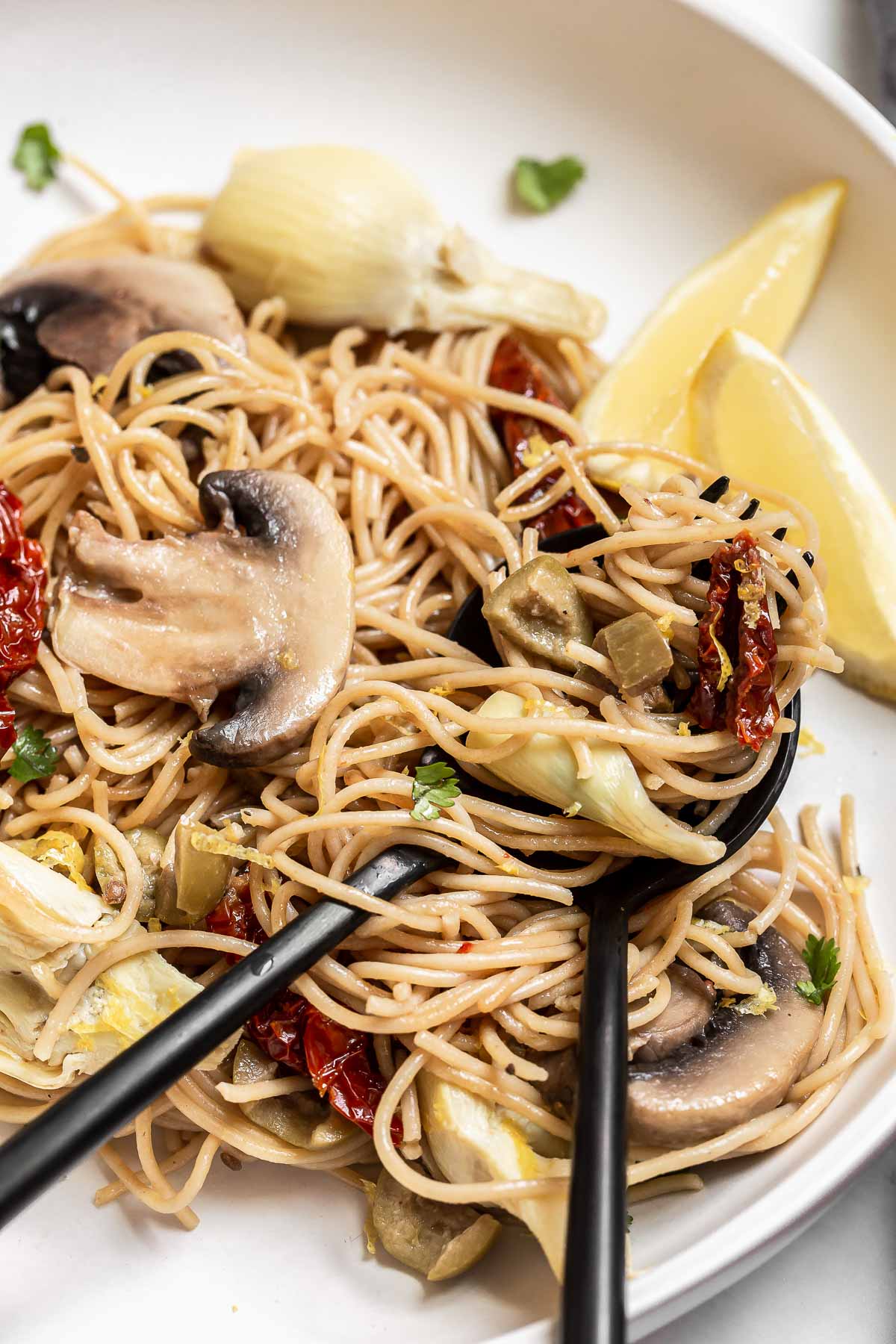 Pasta with vegetables and two forks on a plate.