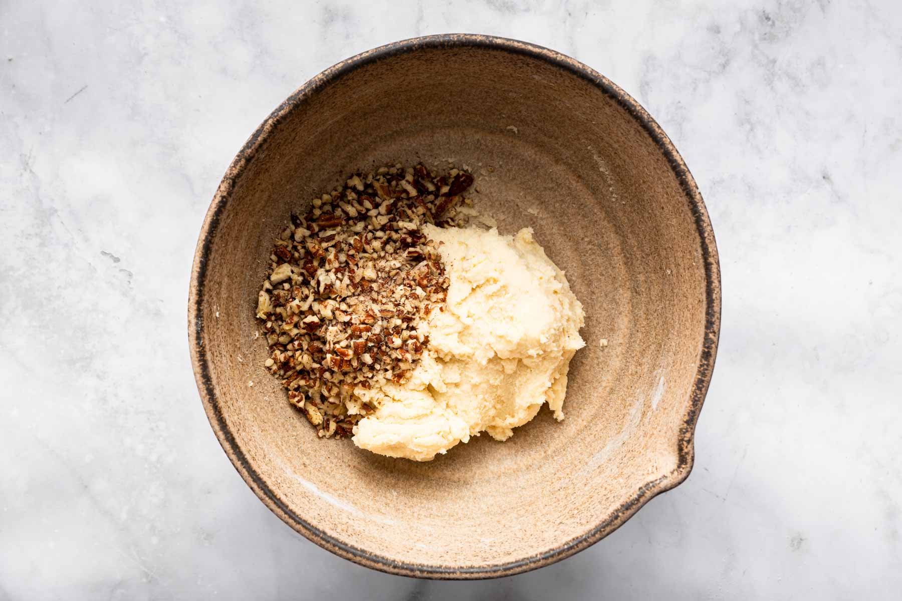 Finely chopped pecans over a clump of cookie dough in bowl.