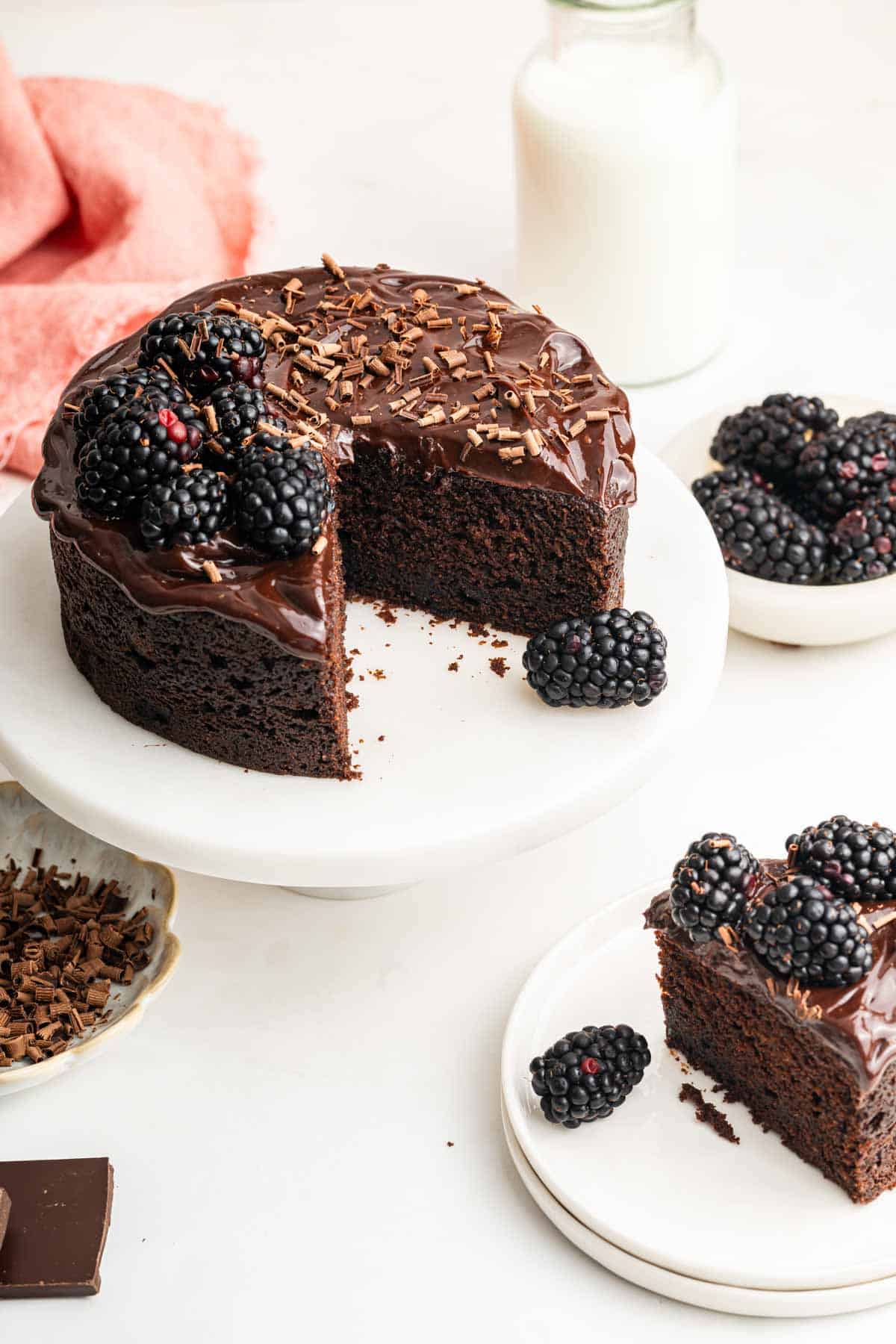 Chocolate cake one white cake stand with one slice missing.