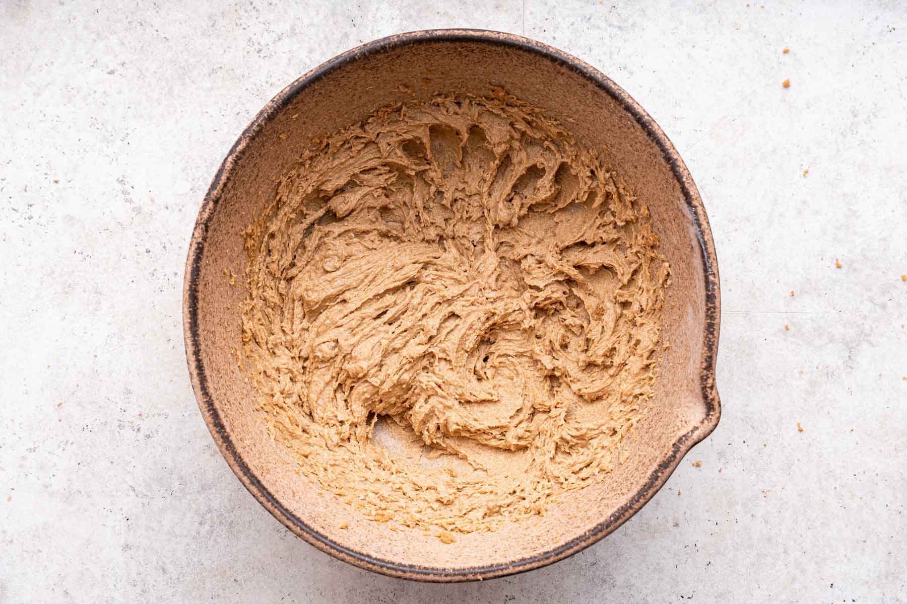 Light brown fluffy cookie dough in a brown mixing bowl.