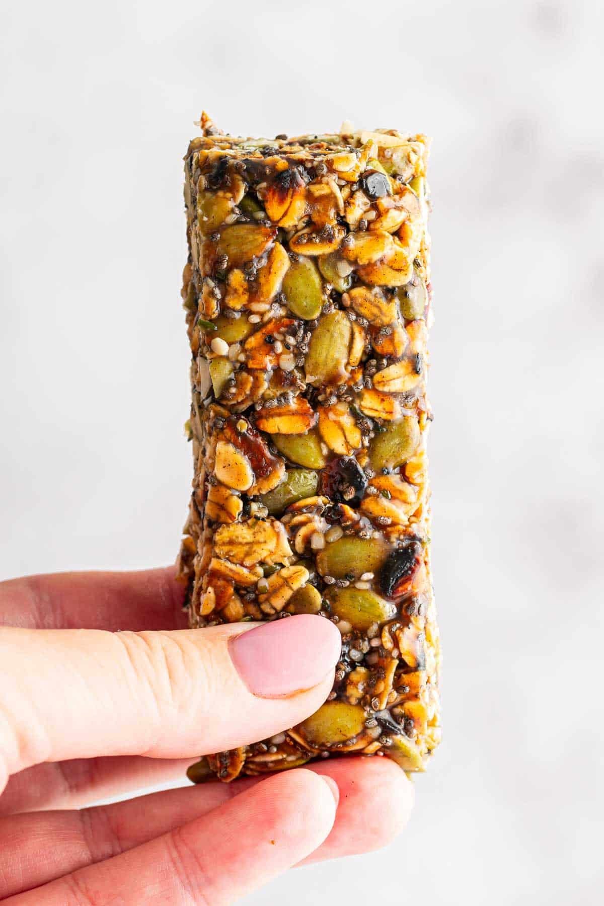 Hand holding a single no bake nut free granola bar.