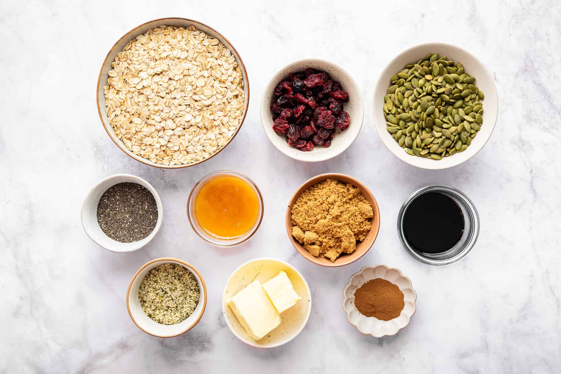 Bowl of oats, pumpkin seeds, brown sugar, melted butter, chia seeds and cranberries.