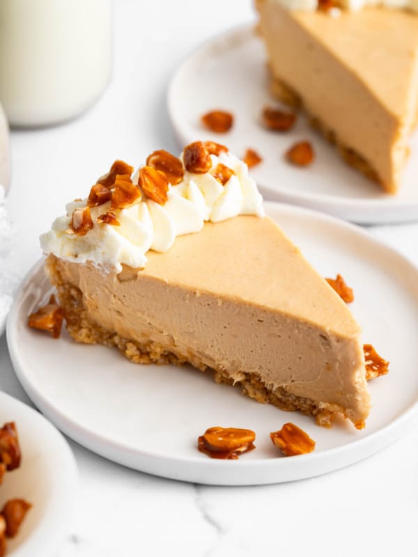 A slice of no bake peanut butter pie on white plate garnished with whipped cream and peanuts.