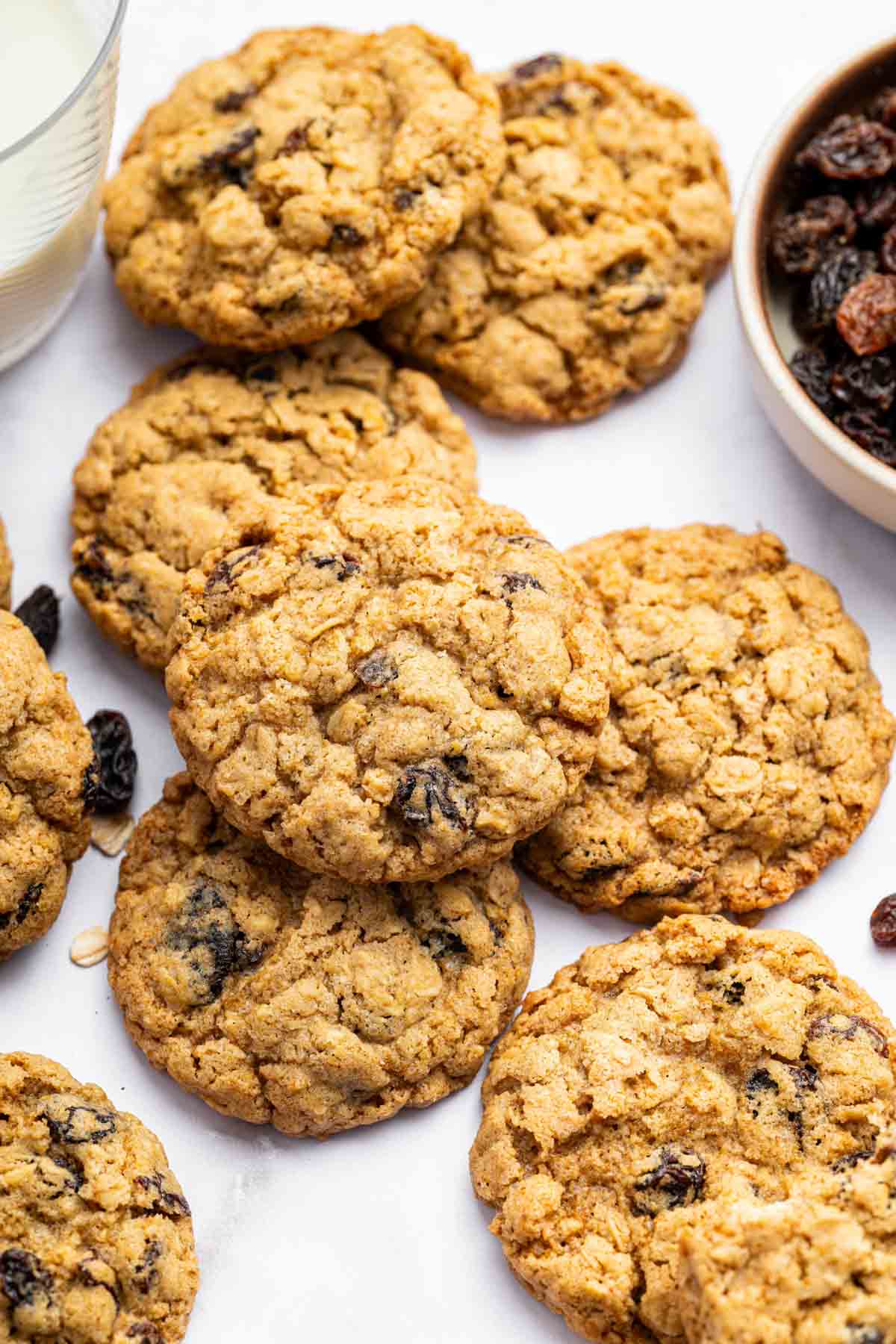 Lay flat image of oatmeal cookies with bowl of raisins on side.