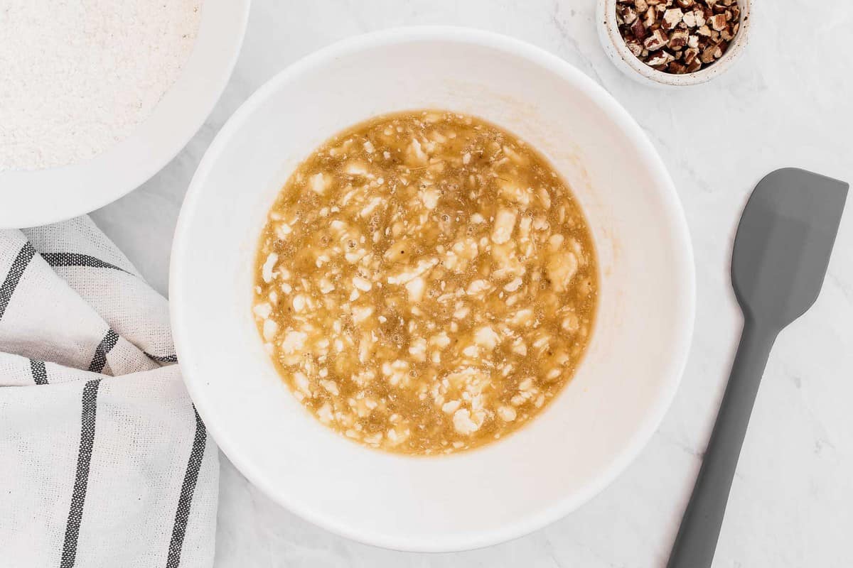 Banana bread ingredients in a bowl, mashed.
