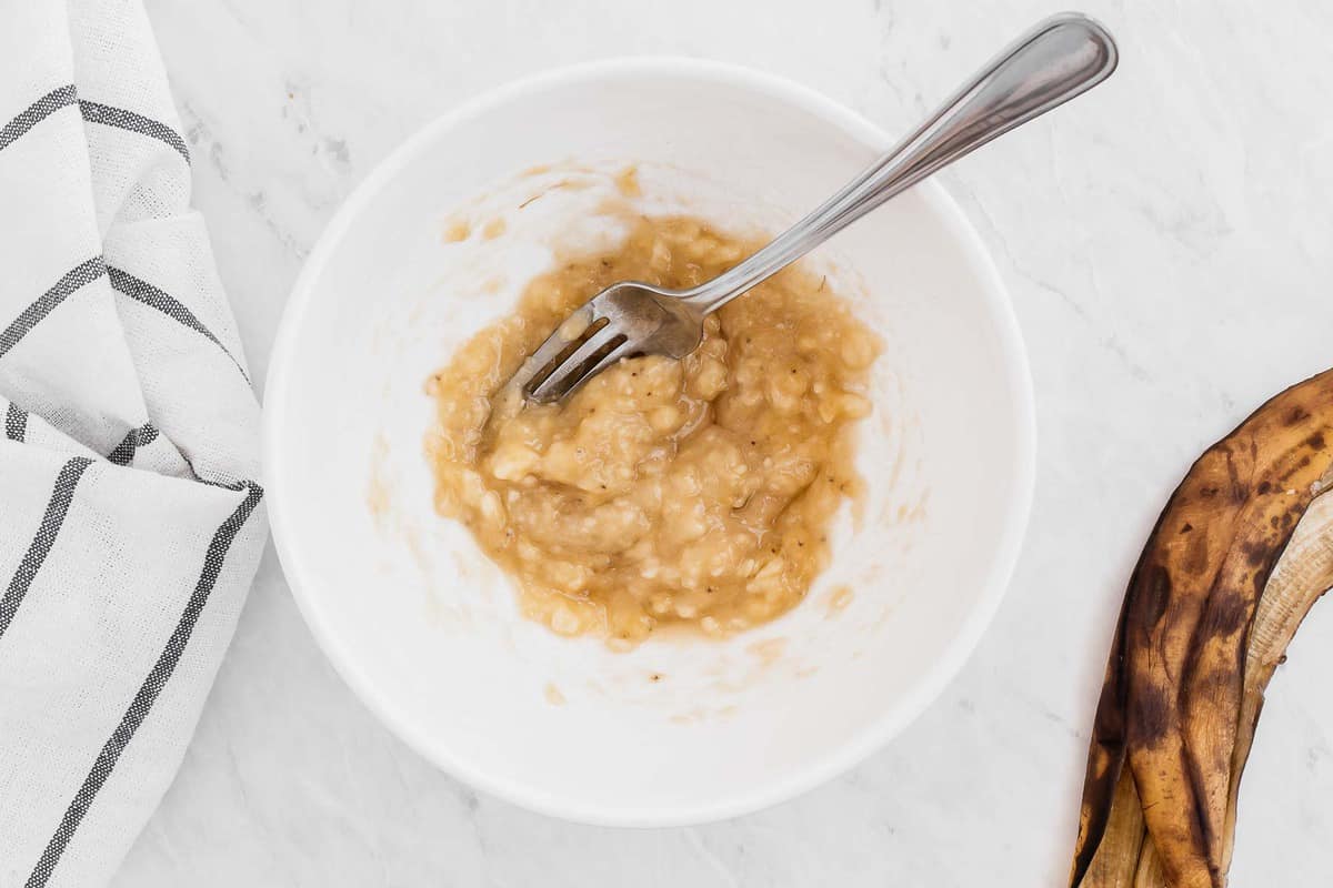 One banana mashed in a white bowl.