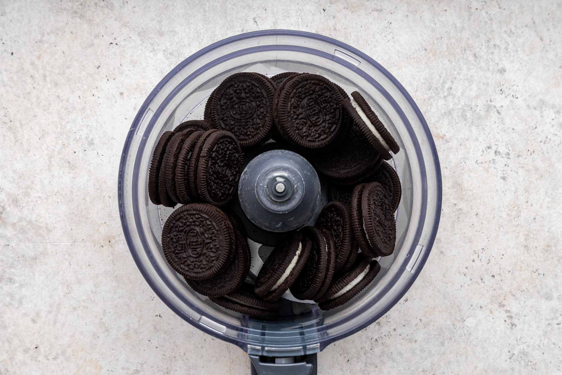 A food processor bowl full of oreo cookies.