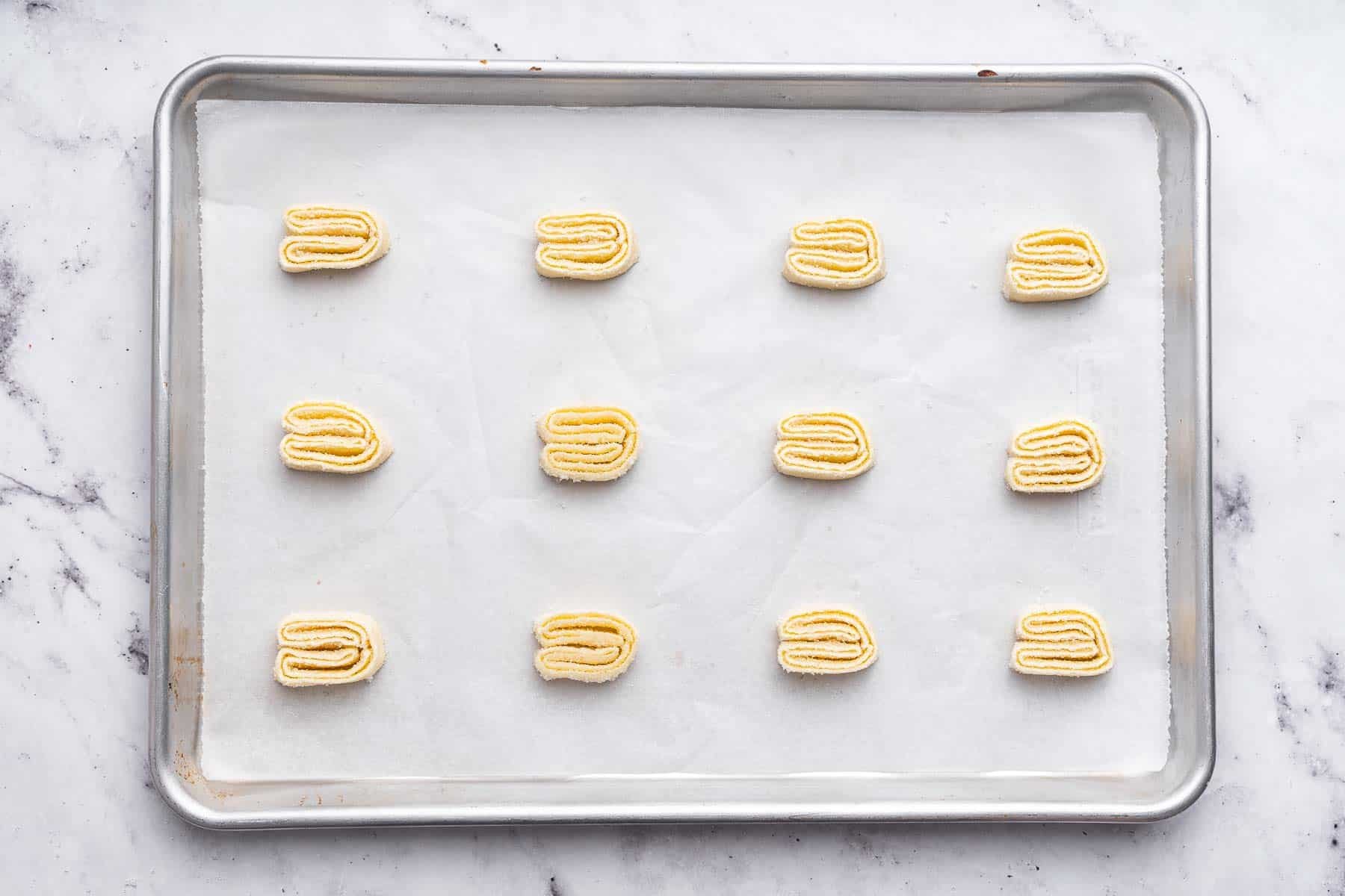 Three rows of cookies on a baking sheet over parchment paper.