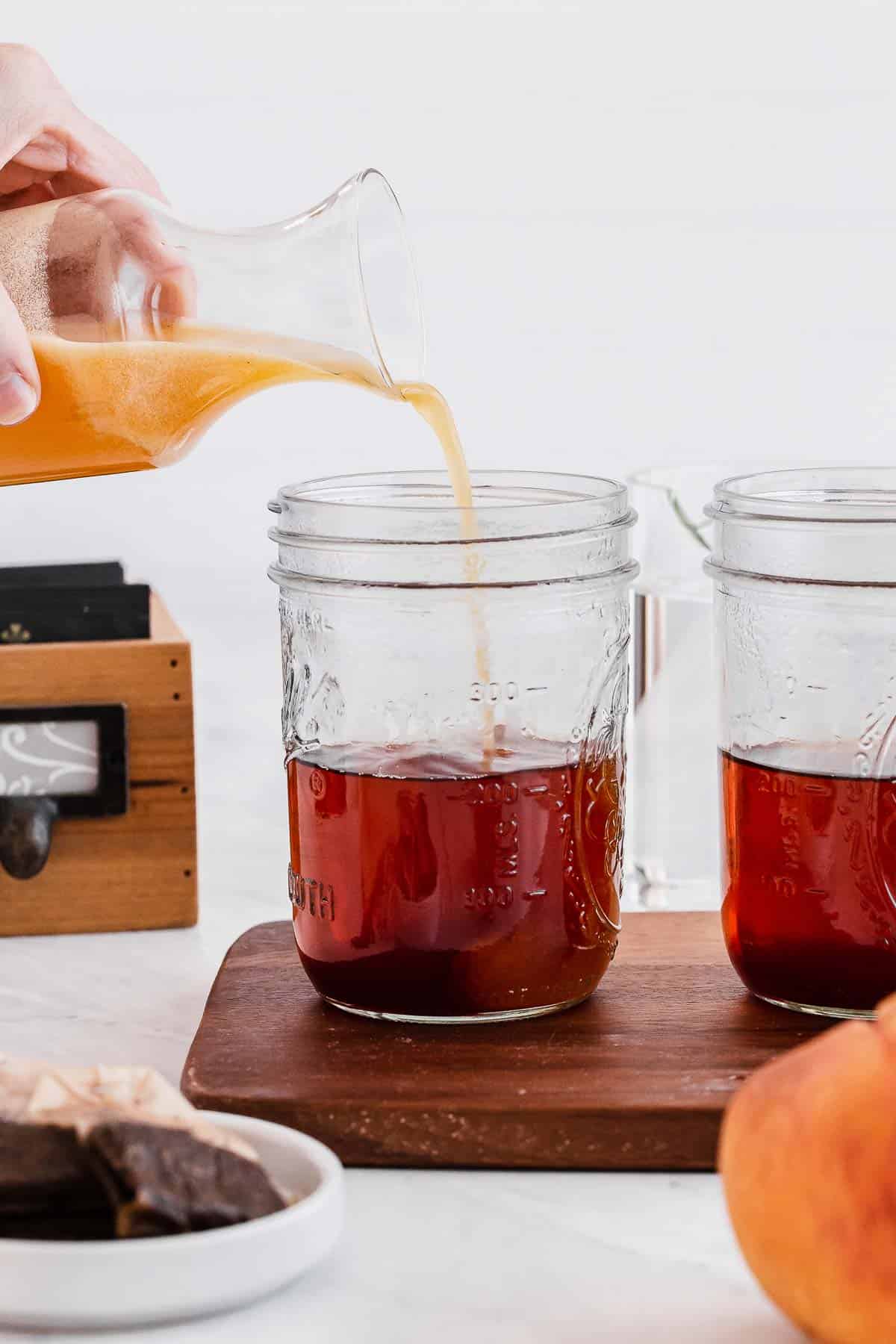 Pouring peach nectar into jar of tea.
