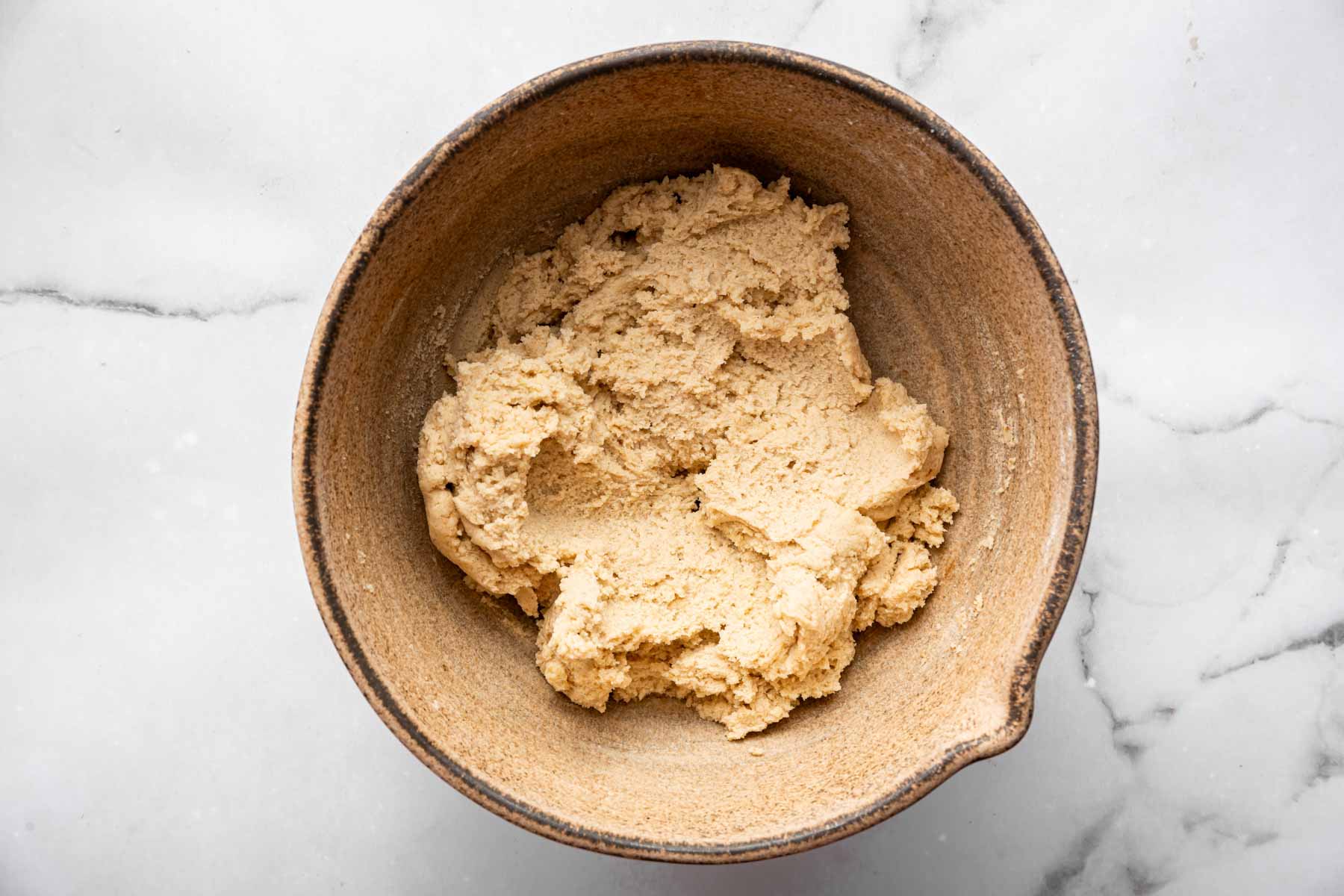 Brown bowl with creamy brown shortbread dough in it.