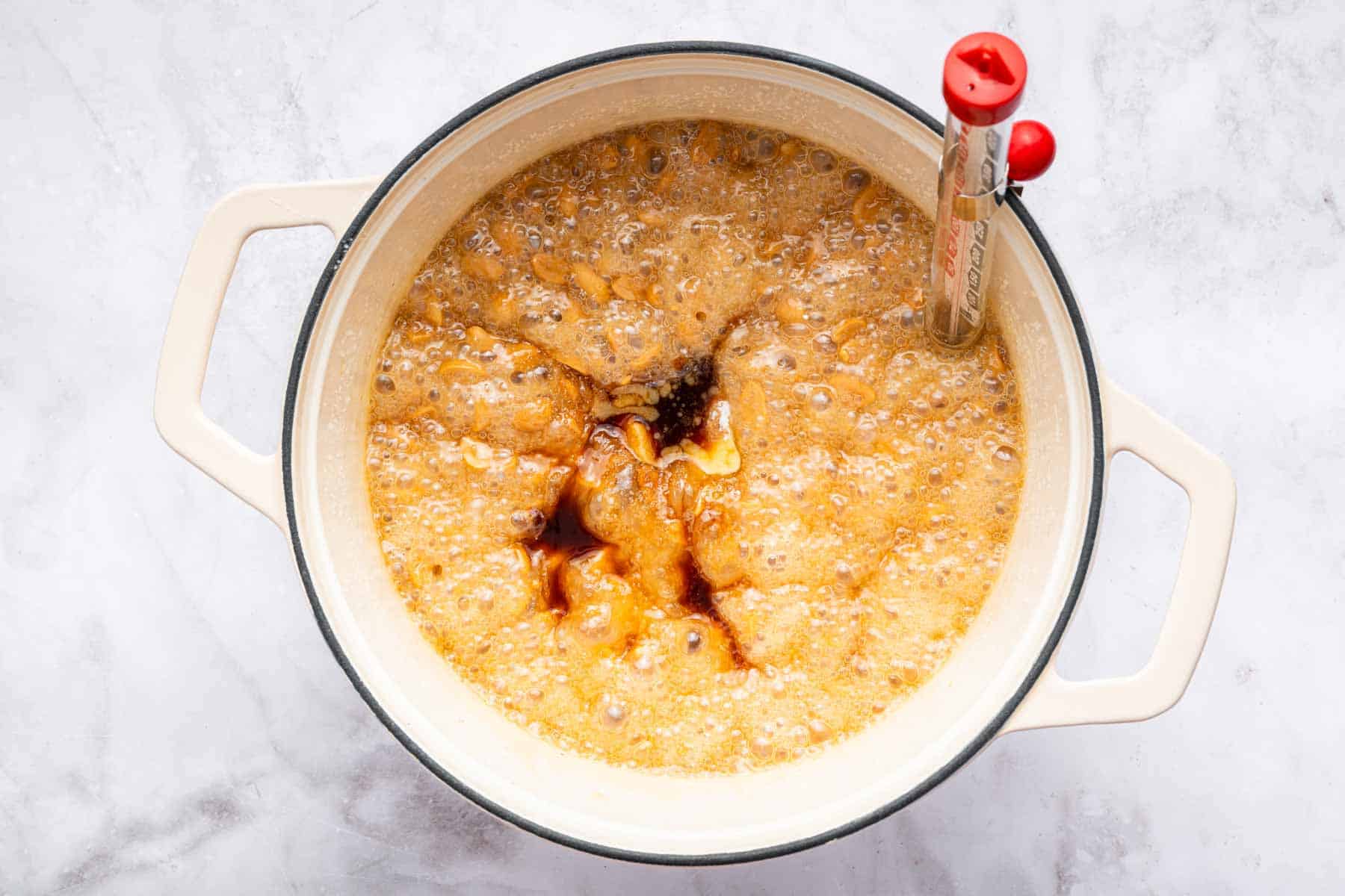 Bubbling sugar in a pot with vanilla splashed on top.