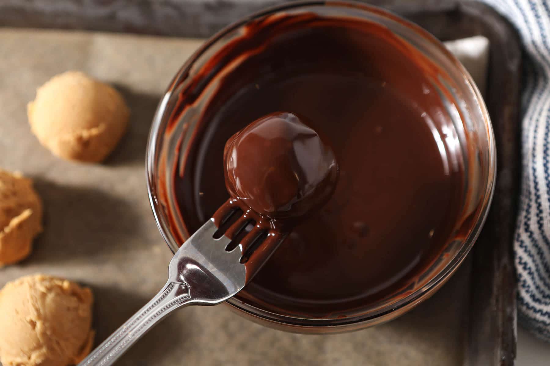 Truffle dunked in chocolate on a fork.