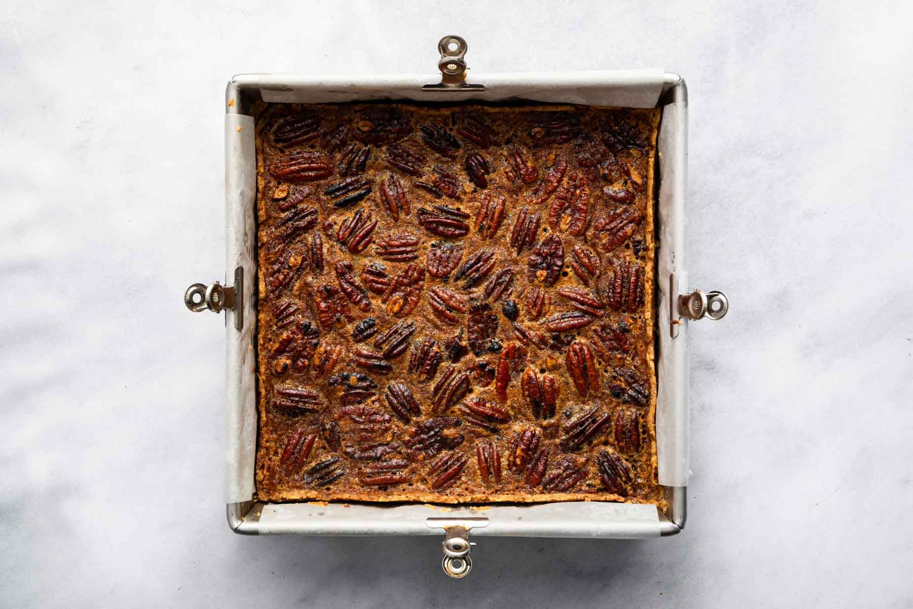 Square pan of pecan pie bars freshly baked.