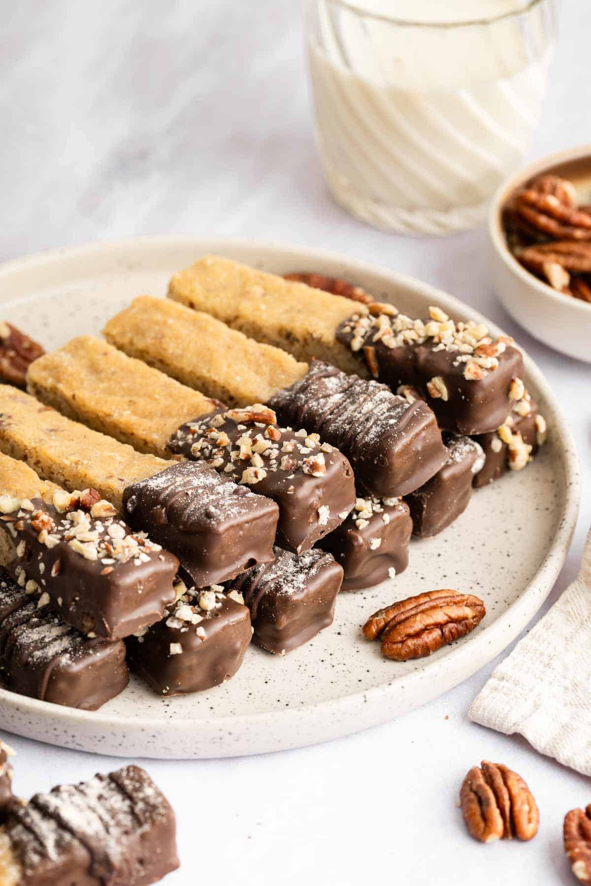 Vertical image of cookie sticks stacked neatly on a plate dipped in chocolate.