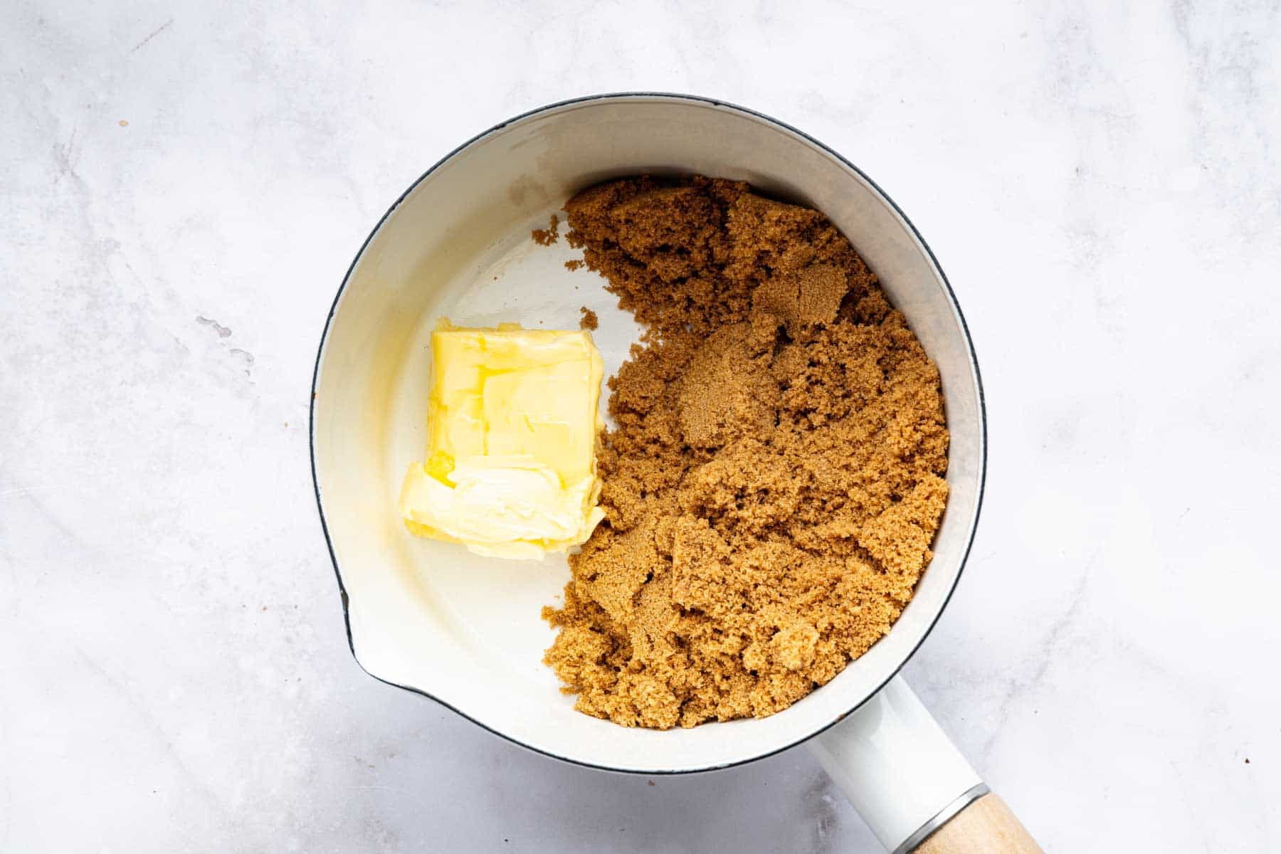 Small white saucepan with butter and brown sugar about to be melted.