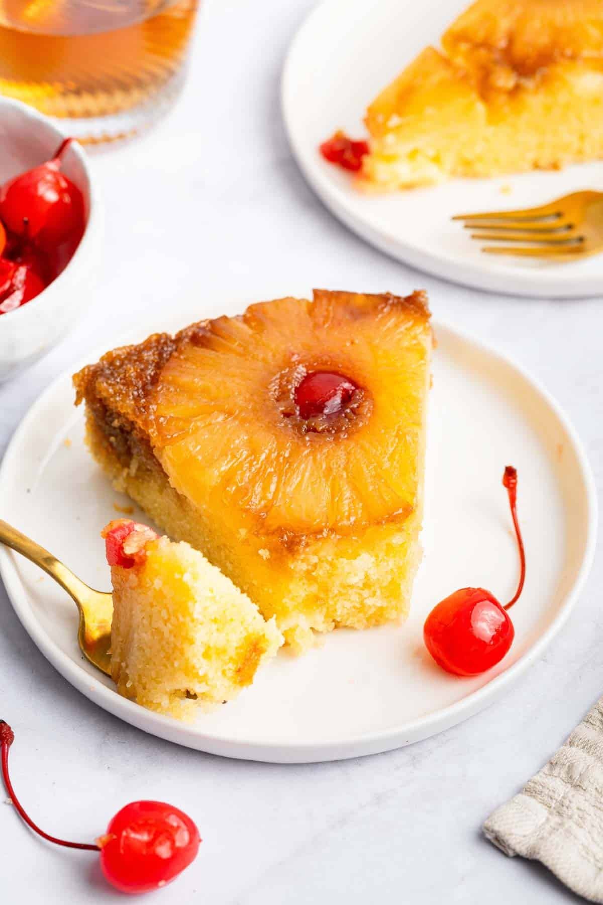 A slice of pineapple upside down cake on a plate with the tip missing.
