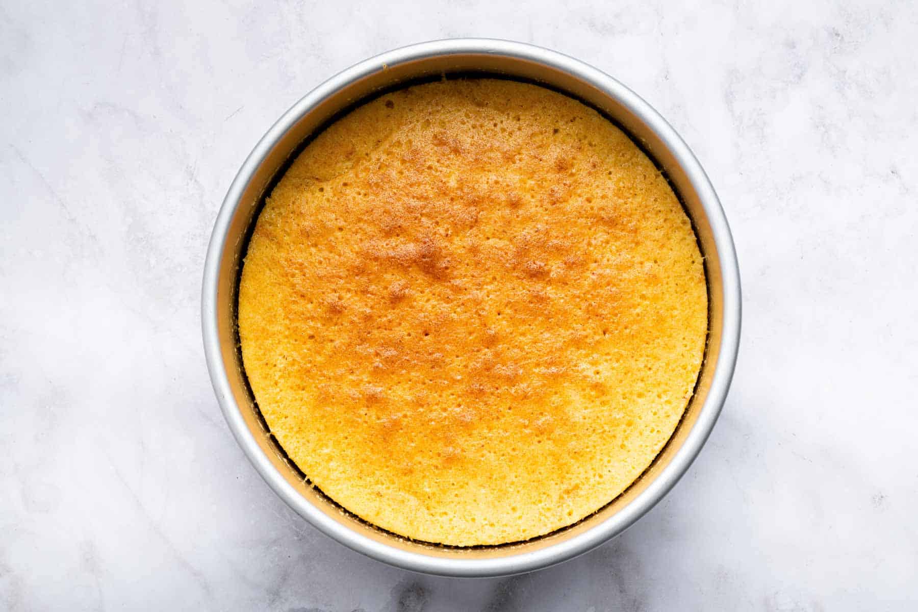 Freshly baked yellow cake in a round cake pan.