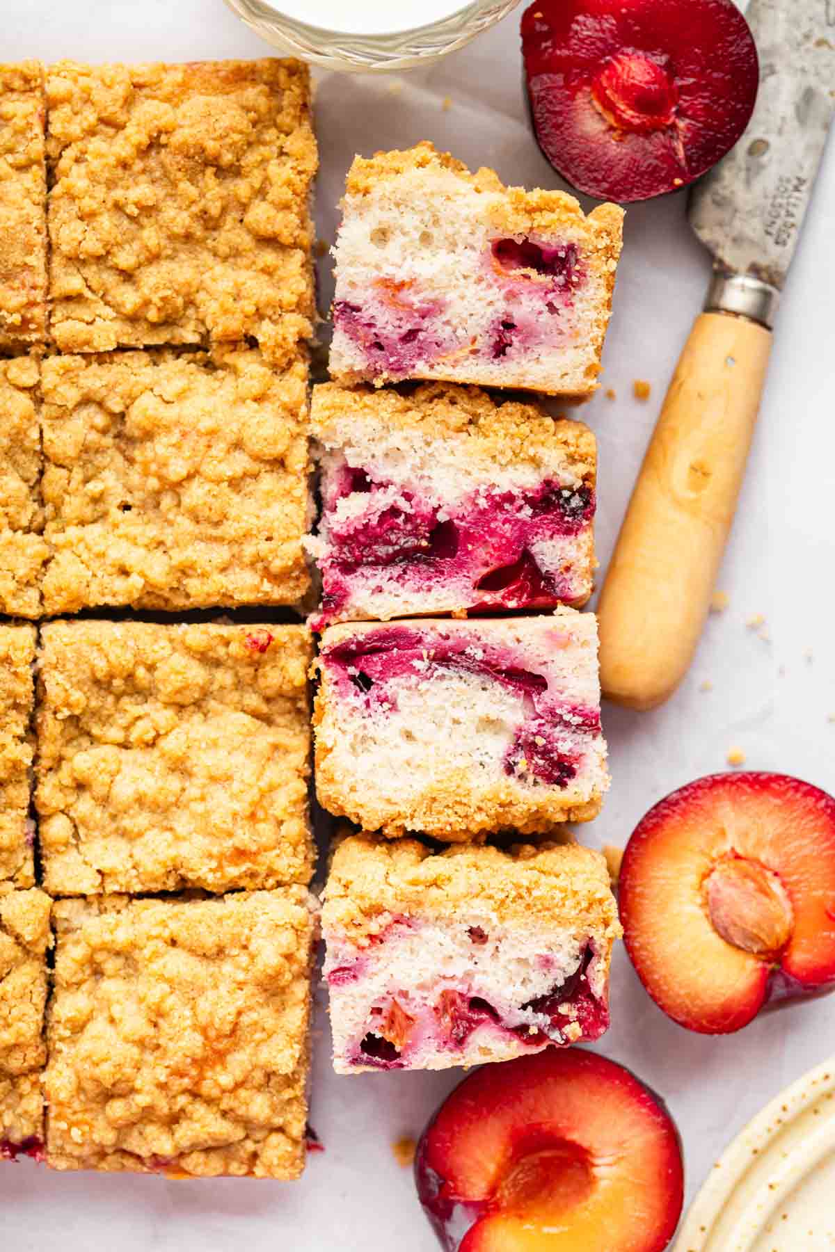 Overhead shot of plum cake with slices laying on side to show fruit bits in the cake.