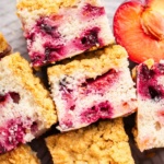 Slices of plum cake with streusel on a platte with a half plum nearby.