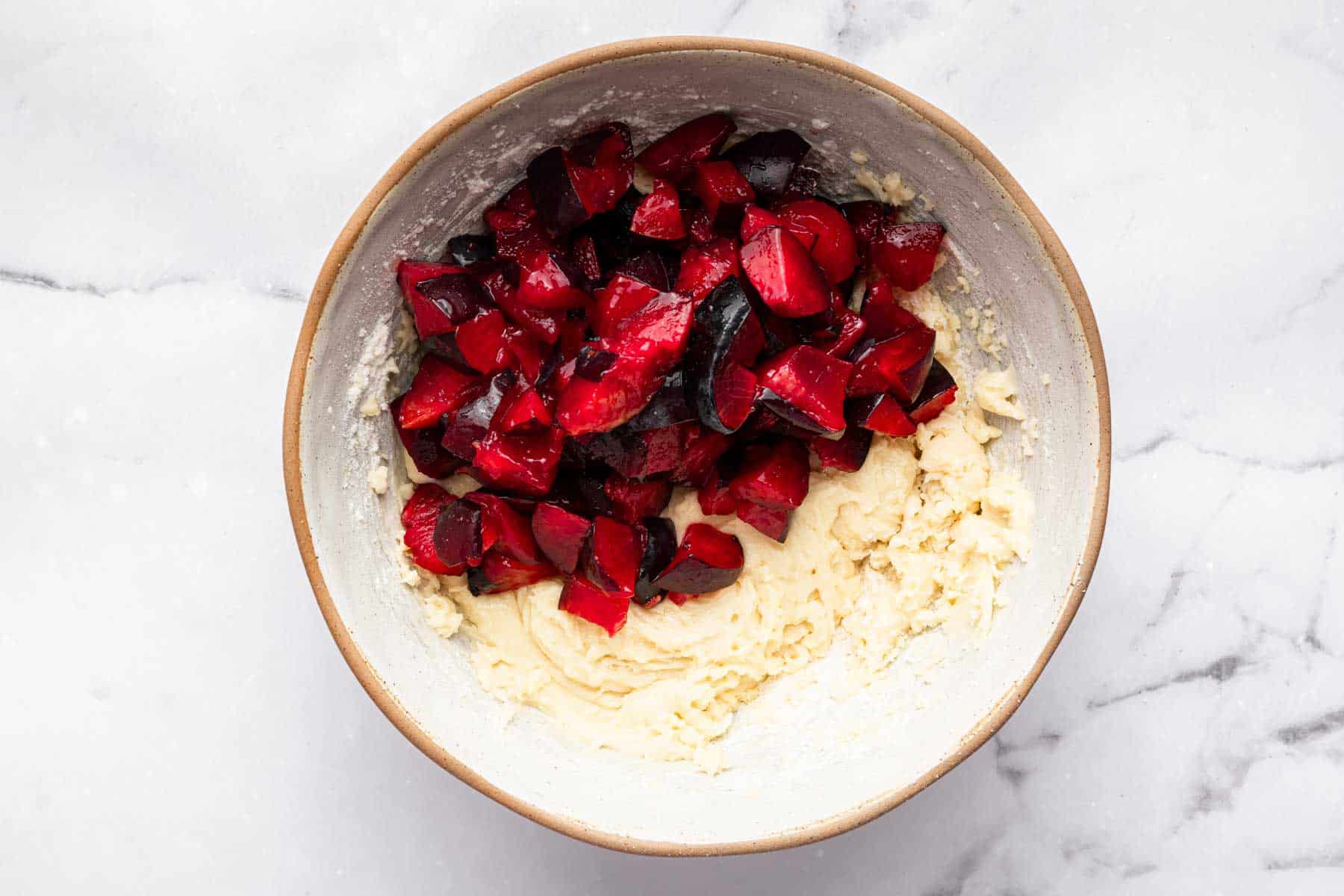 Yellow raw batter with diced red fruit on top.