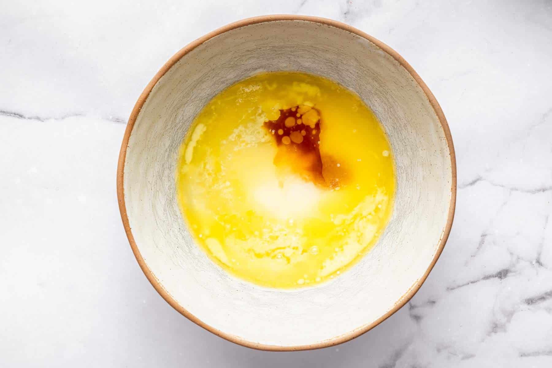 Mixing bowl with melted butter, sugar and a splash of brown vanilla.