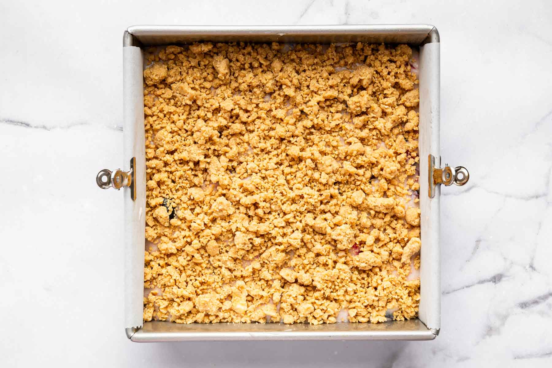 Square dessert with big streusel chunks on top before baking.