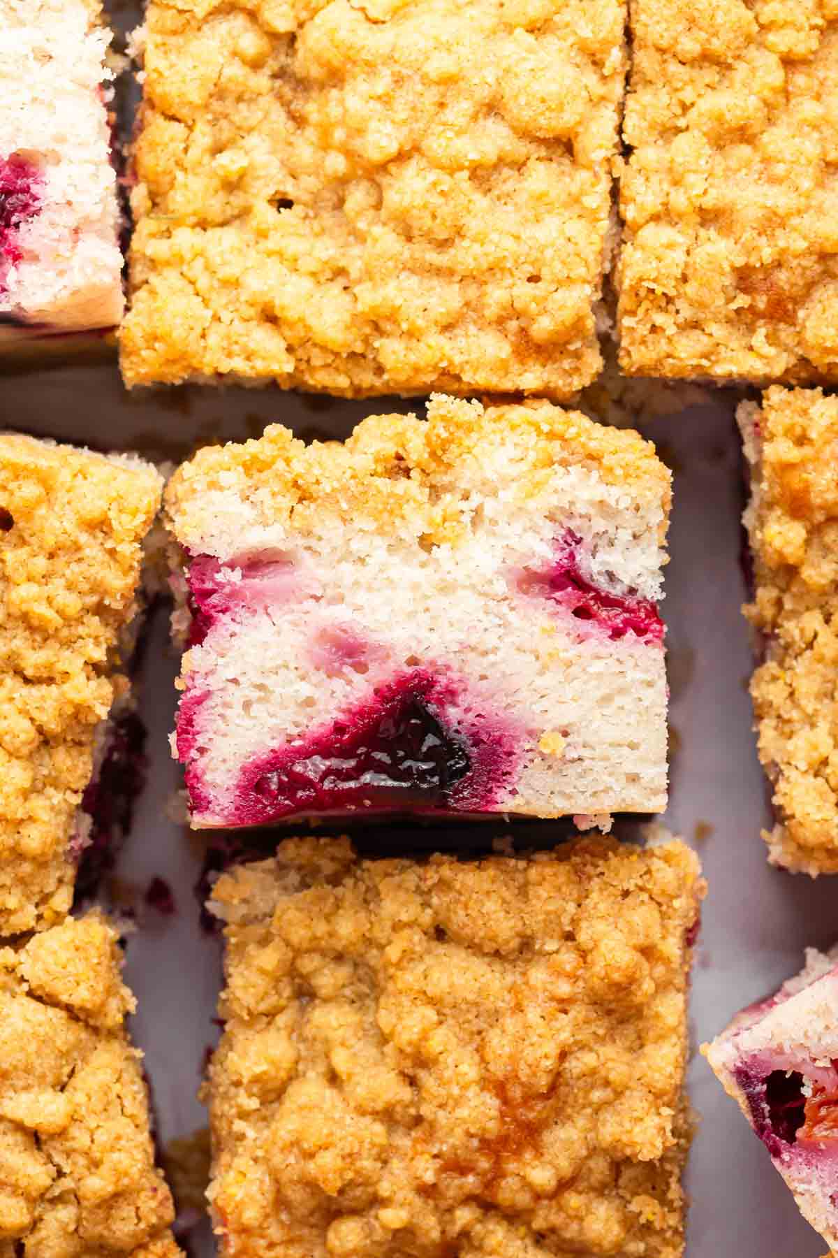 Slice of plum cake with streusel turned on its side to show interior.