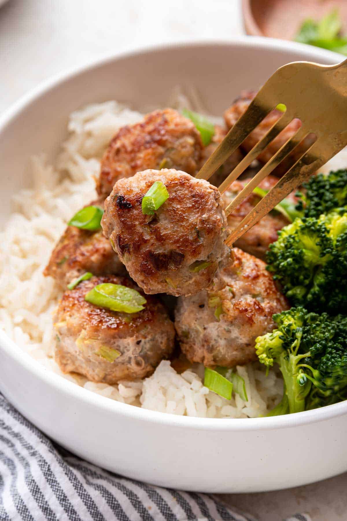 Bowl of rice with pork meatballs and steamed broccoli.