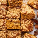 Squares of pumpkin coffee cake on table with a mini pumpkin.