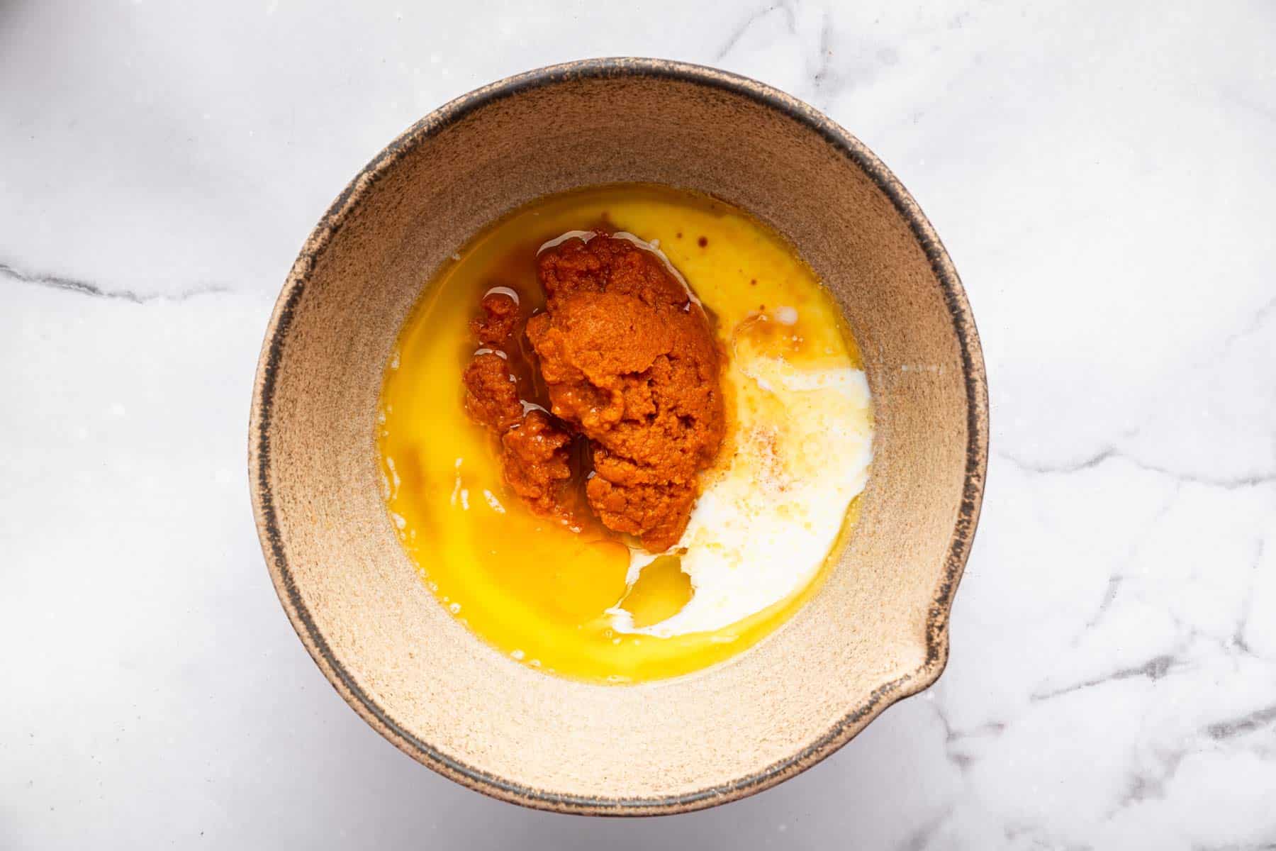 Brown bowl with melted butter and orange batter.