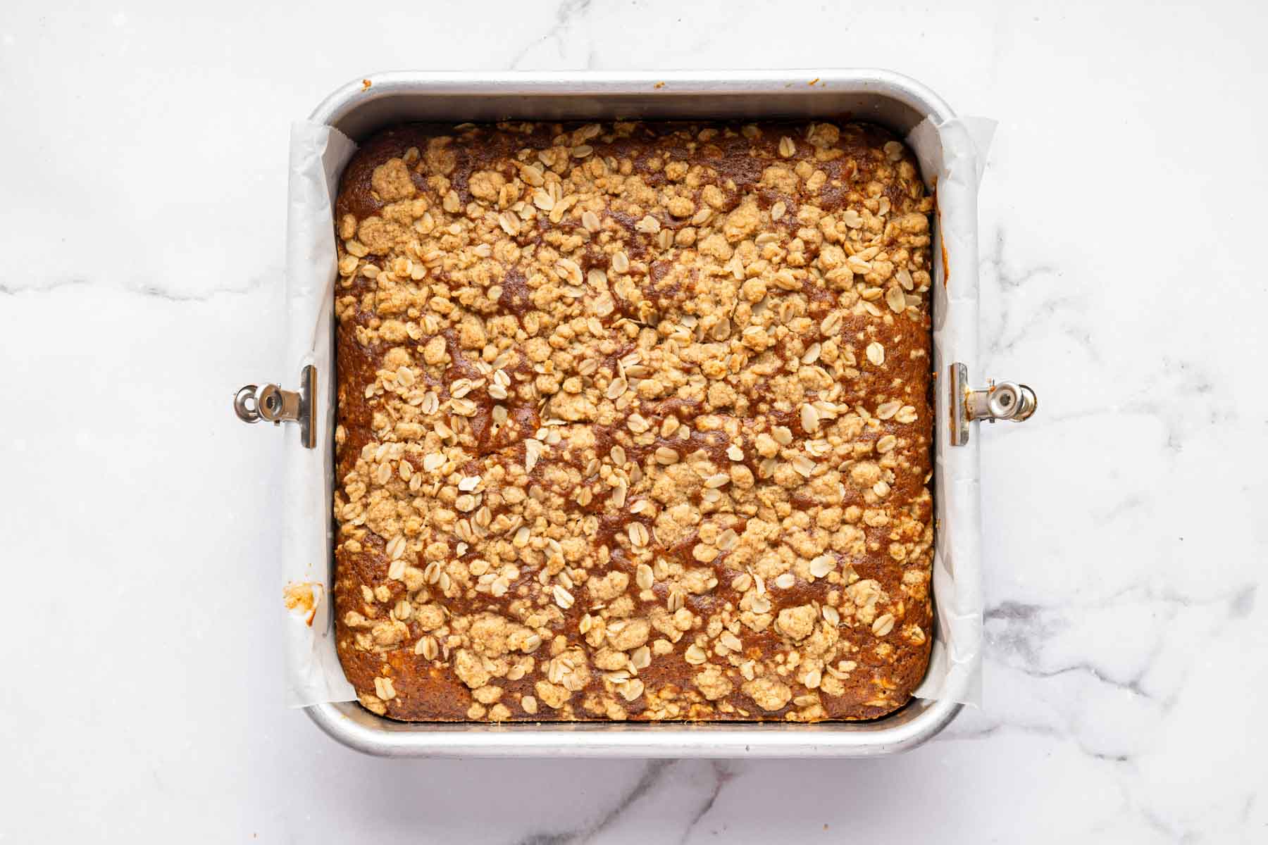 Freshly baked pumpkin coffee cake with crumb topping in a square pan.