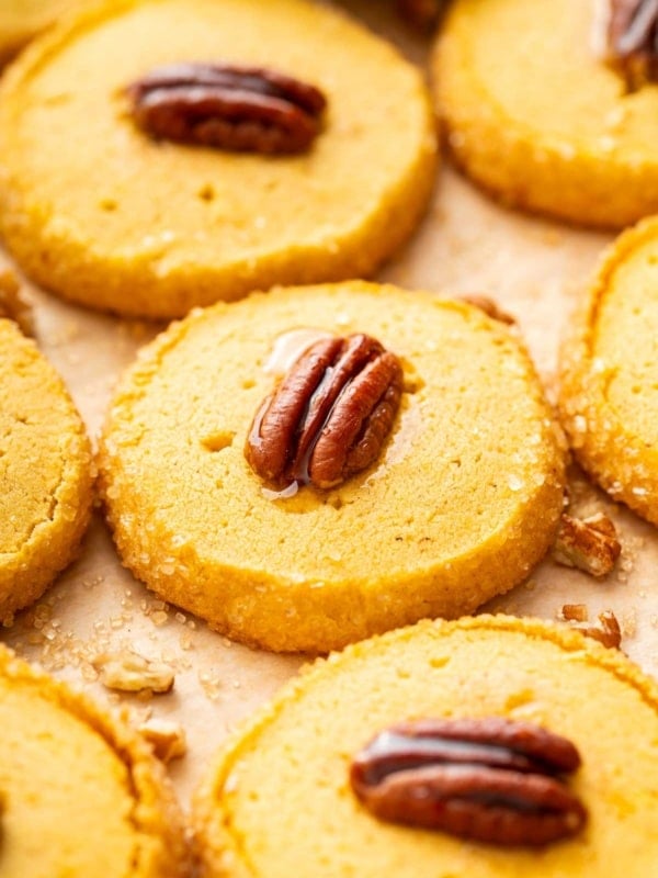 Orange pumpkin shortbread with a glazed pecan on top of each cookie.