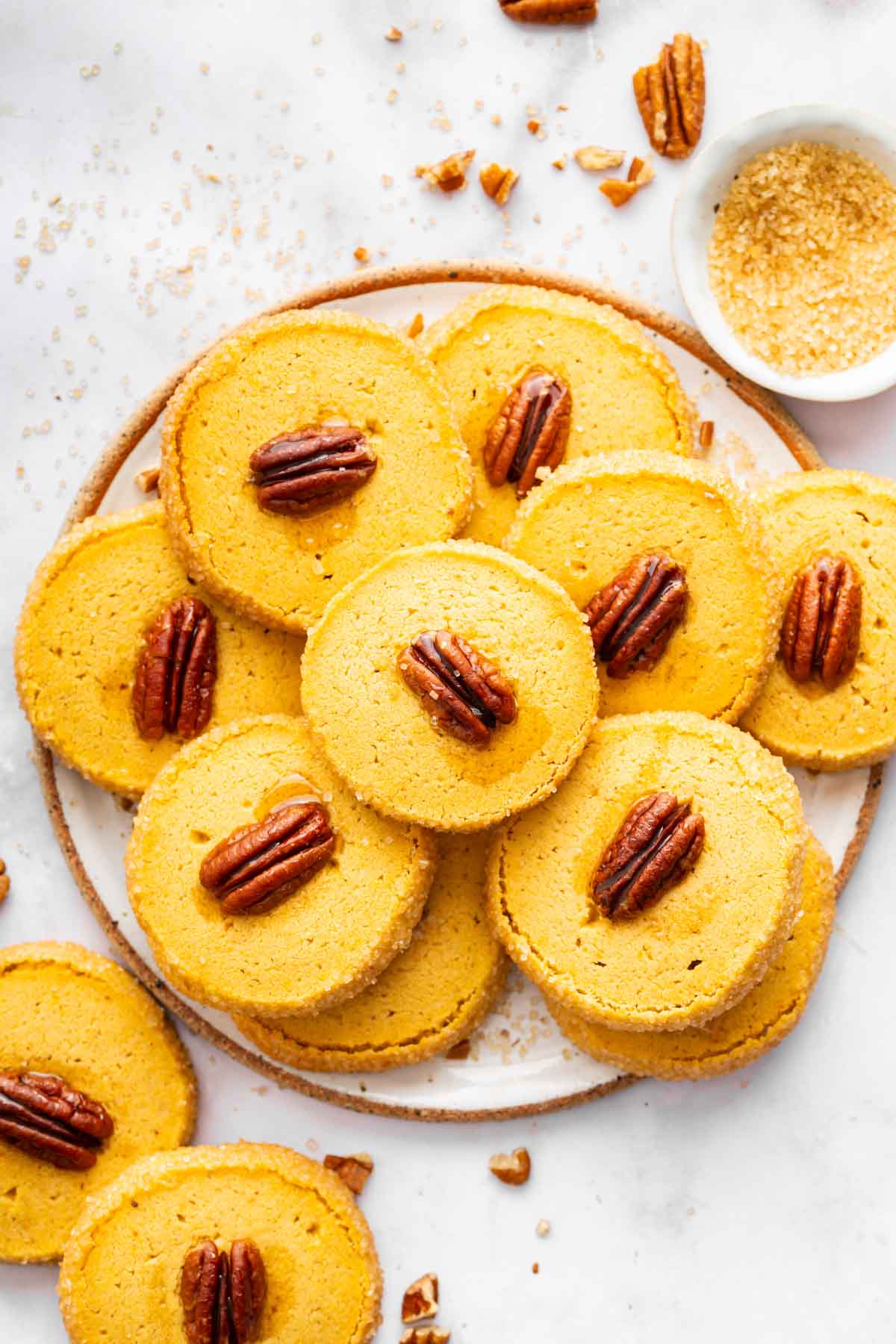 Orange pecan topped cookies on white round plate.