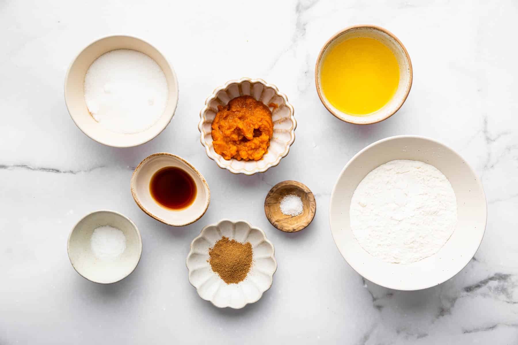 Small bowls of melted butter, flour, spices, and vanilla for baking.