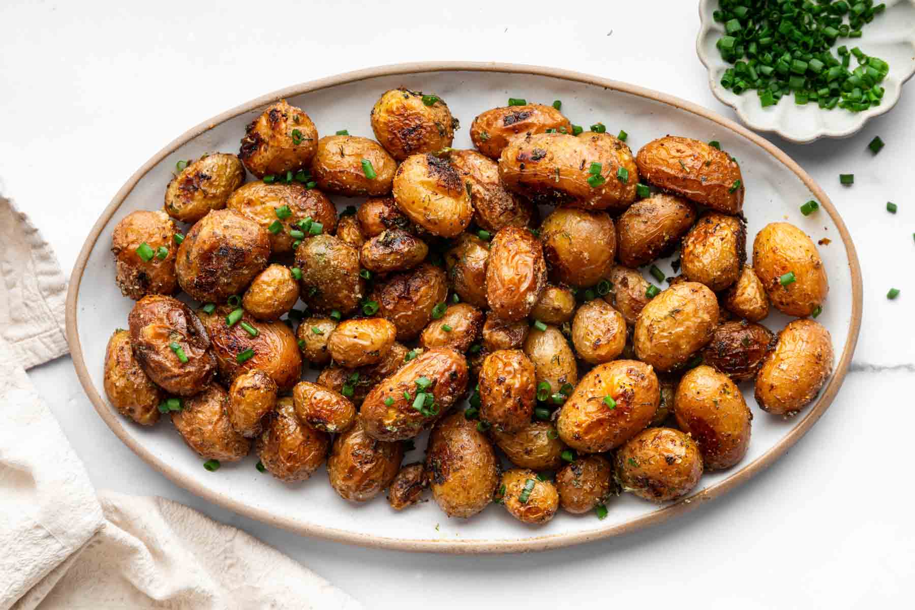 Serving dish full of roasted vegetables with chives sprinkled on top.
