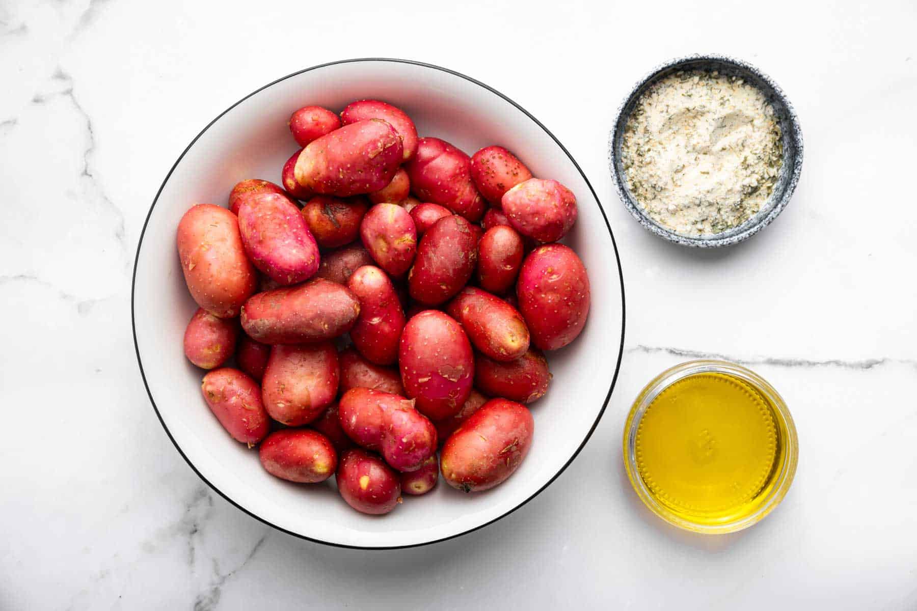Bowl of small red root veggies with spices and olive oil on the side.