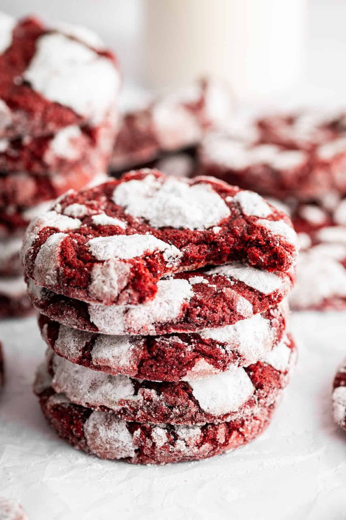 Stack of red velvet crinkle cookies on white surface.