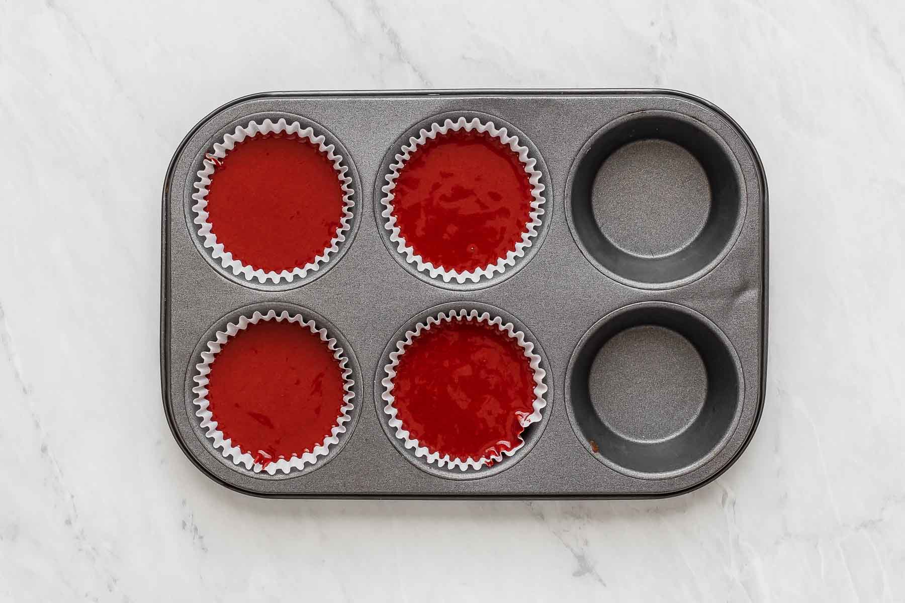 Four red velvet cupcakes in a pan.