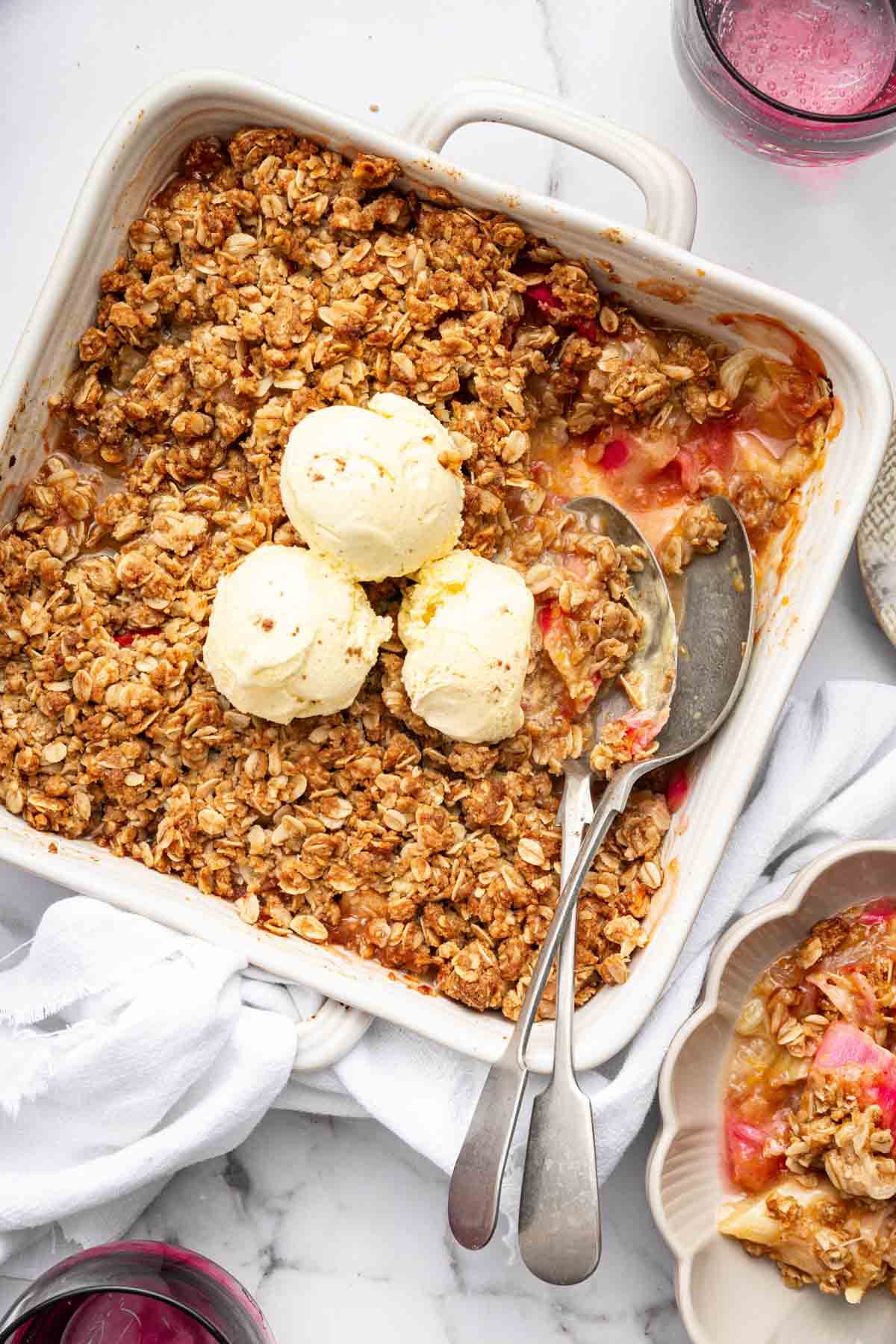 Square dish with fruit dessert topped with 3 scoops of vanilla ice cream.
