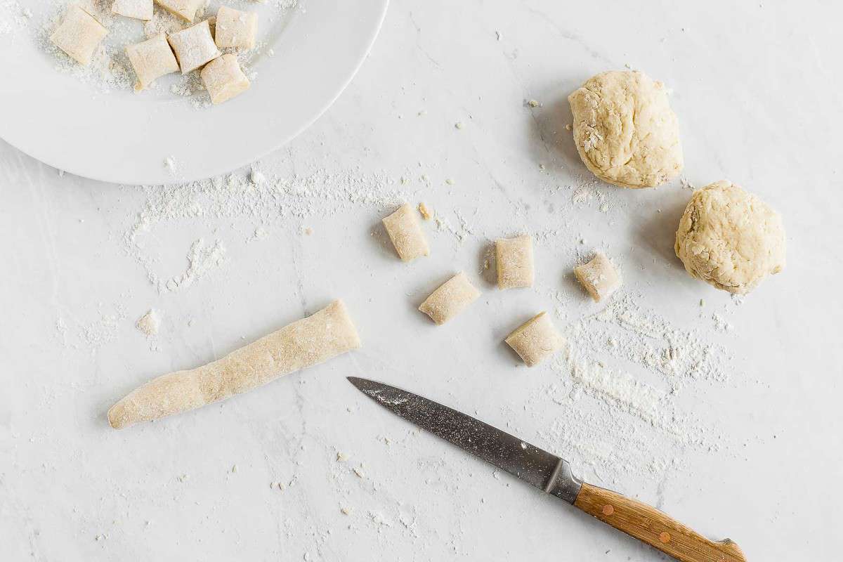 Raw gnocchi dough being rolled and cut into shapes.