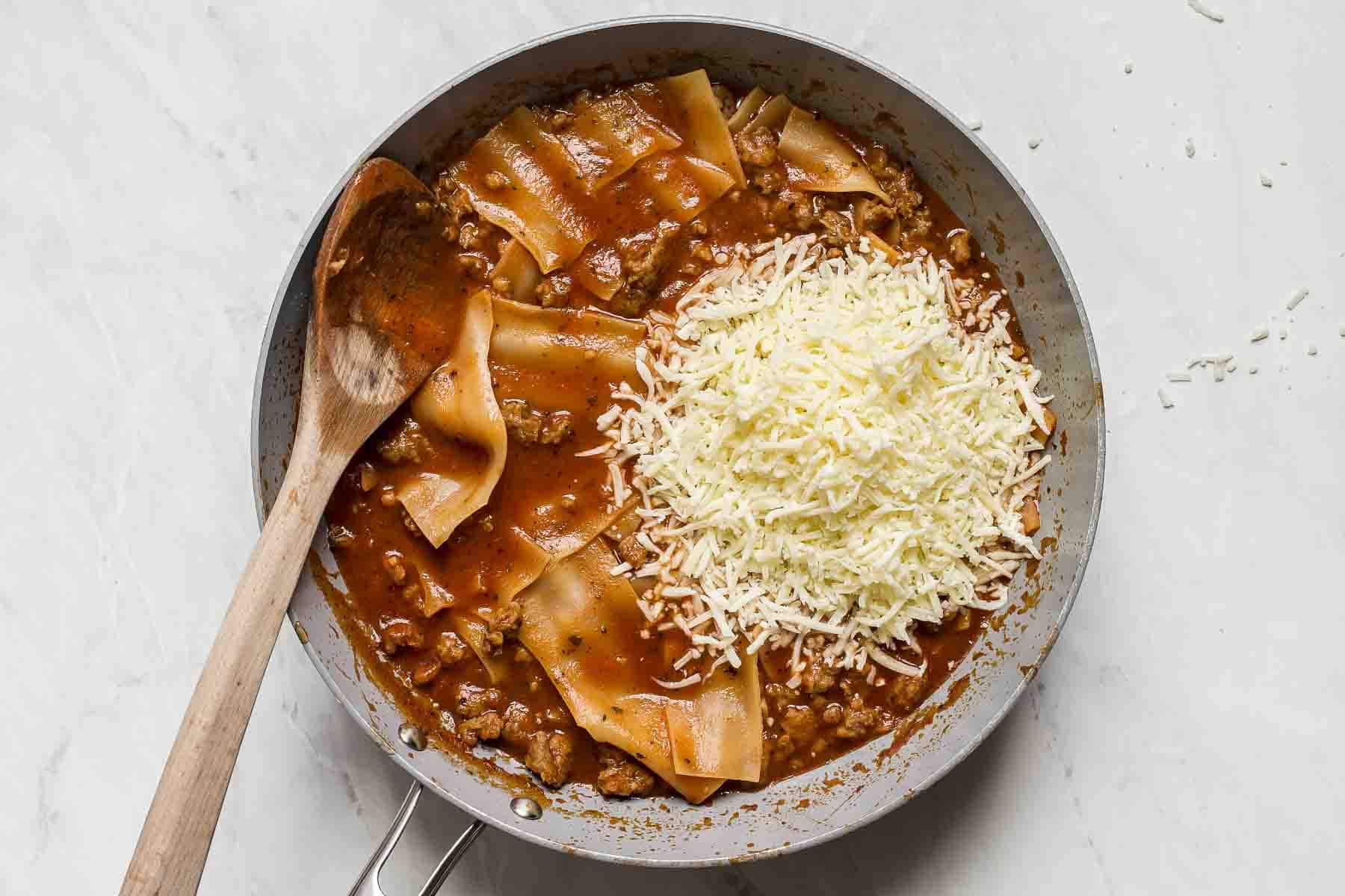 Shredded mozzarella in a skillet of pasta.