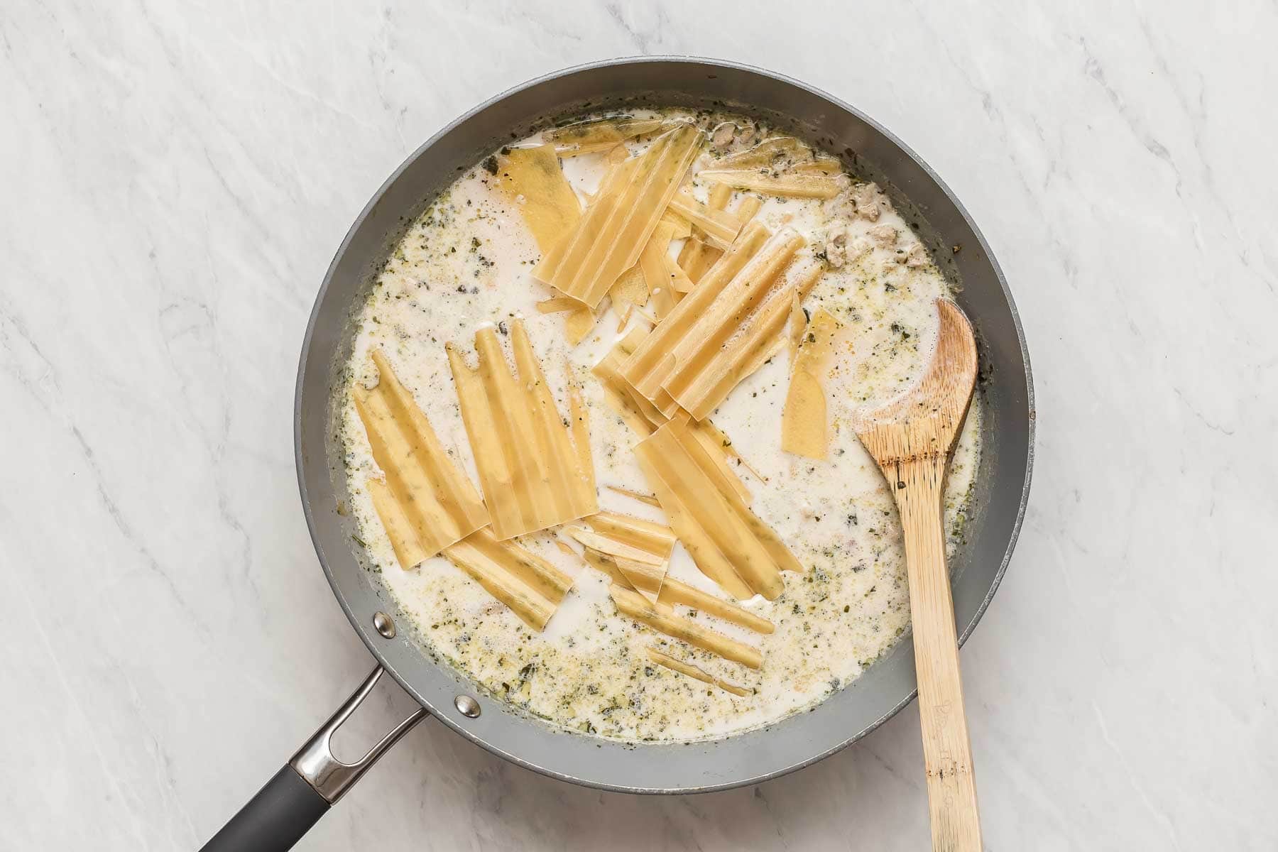 Broken lasagna noodles in a skillet bรฉchamel sauce.