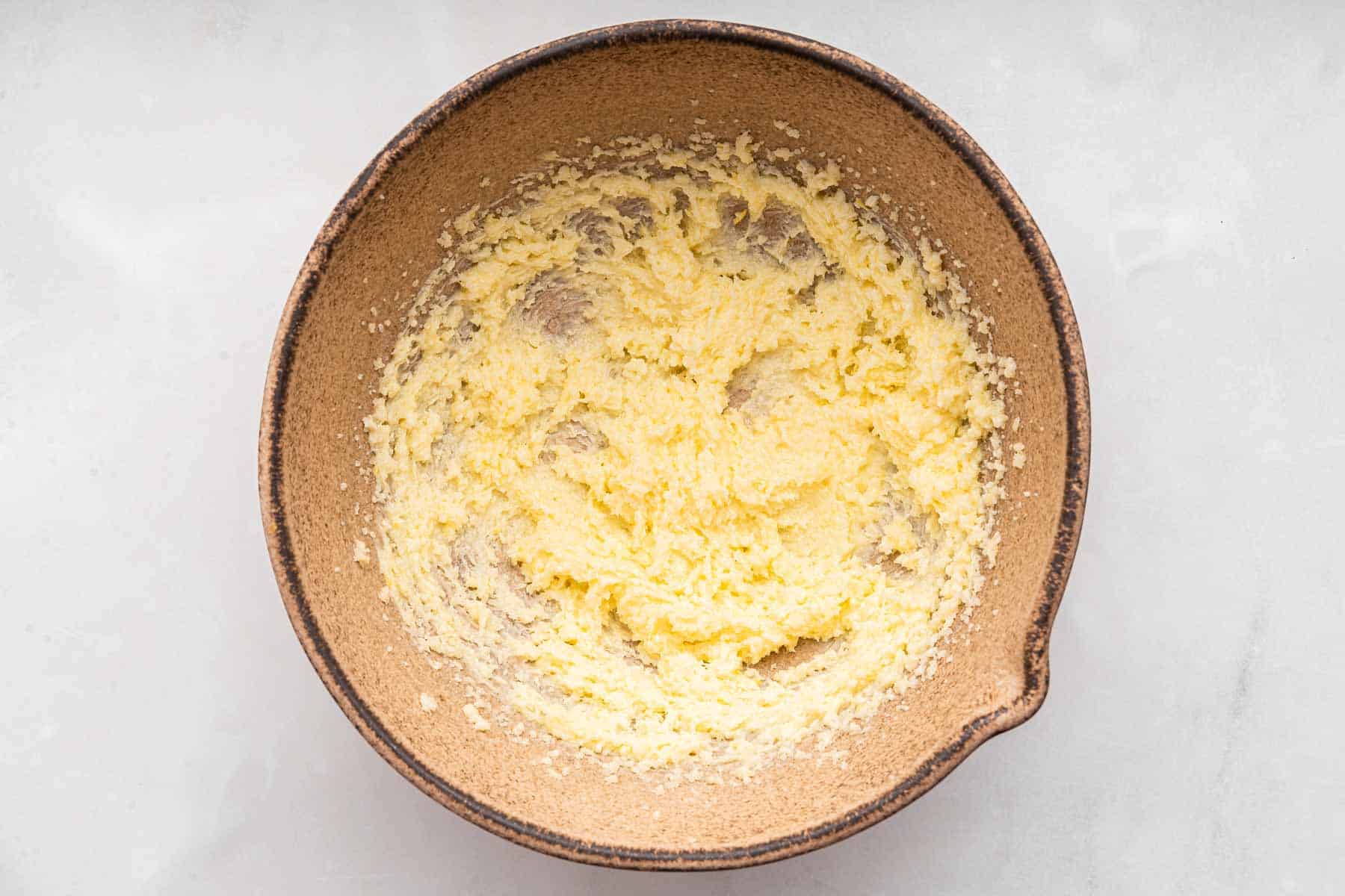 Brown bowl with fluffy yellow batter beat.