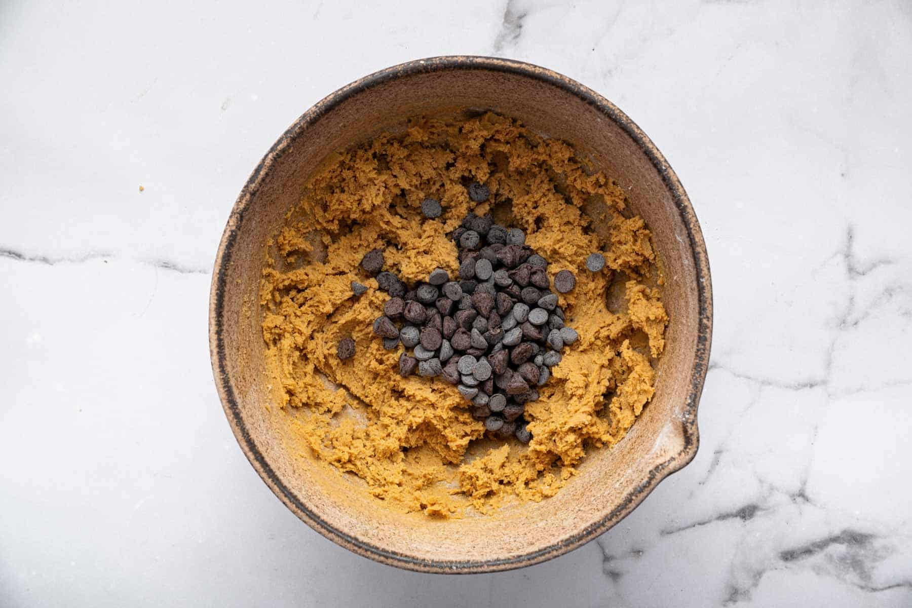 Chocolate chips in a bowl with brown batter.
