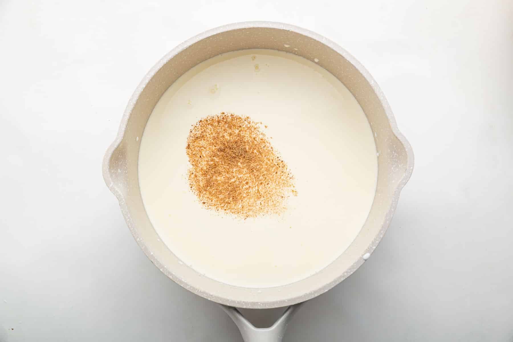 Milk in saucepan with nutmeg on top.