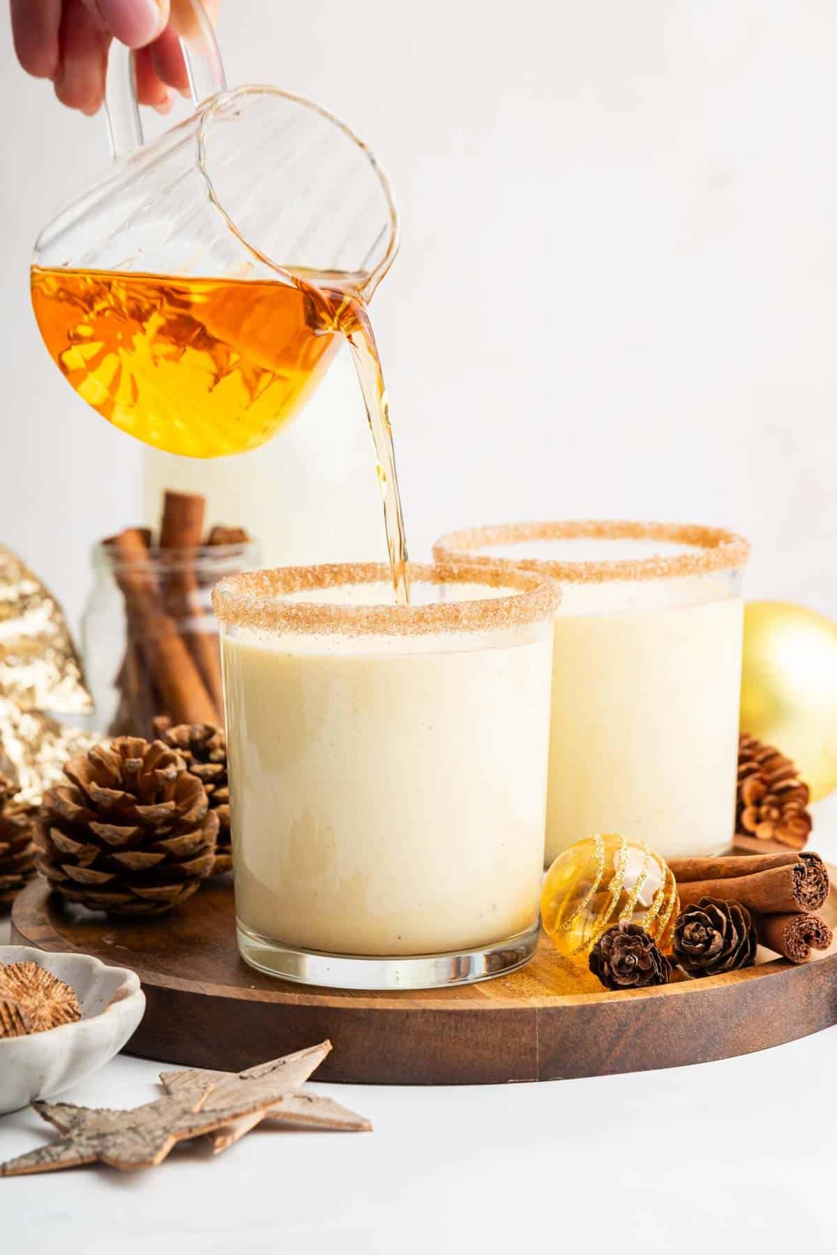 Amber liquid being poured into cups of a white drink.
